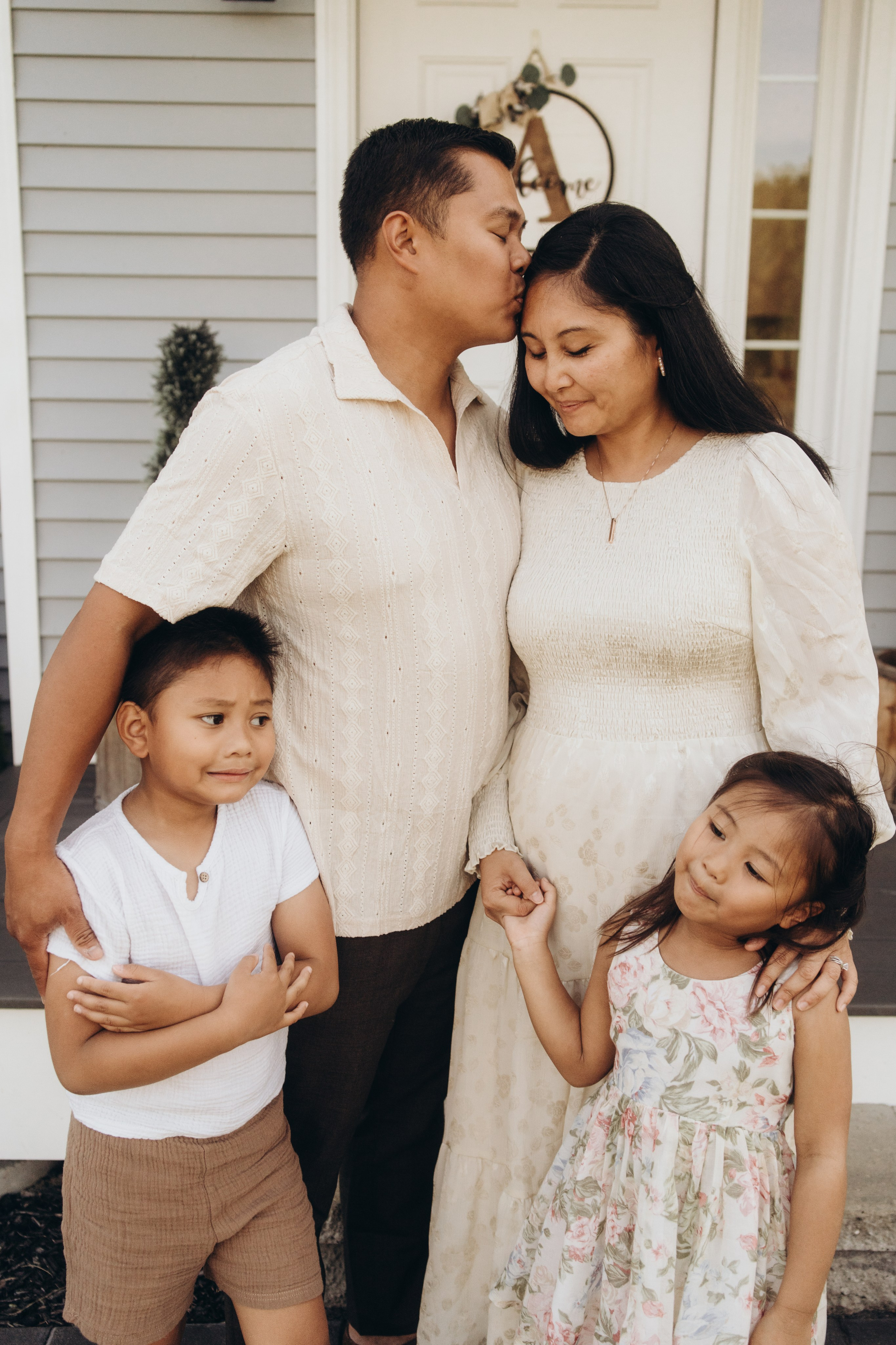 Parents sharing a kiss on the porch while their children hug them