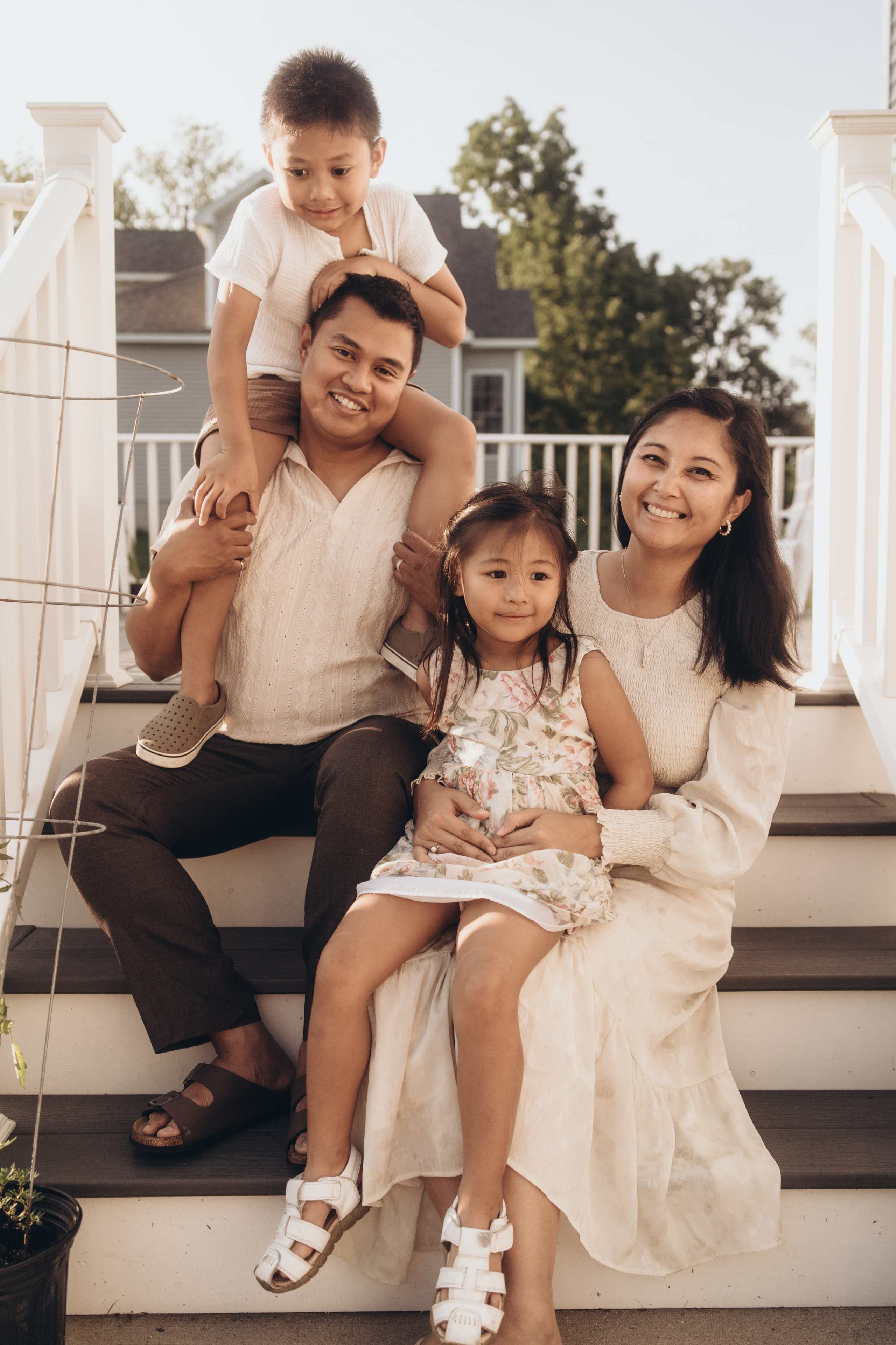 Family sitting on the front steps, son on his father’s shoulders