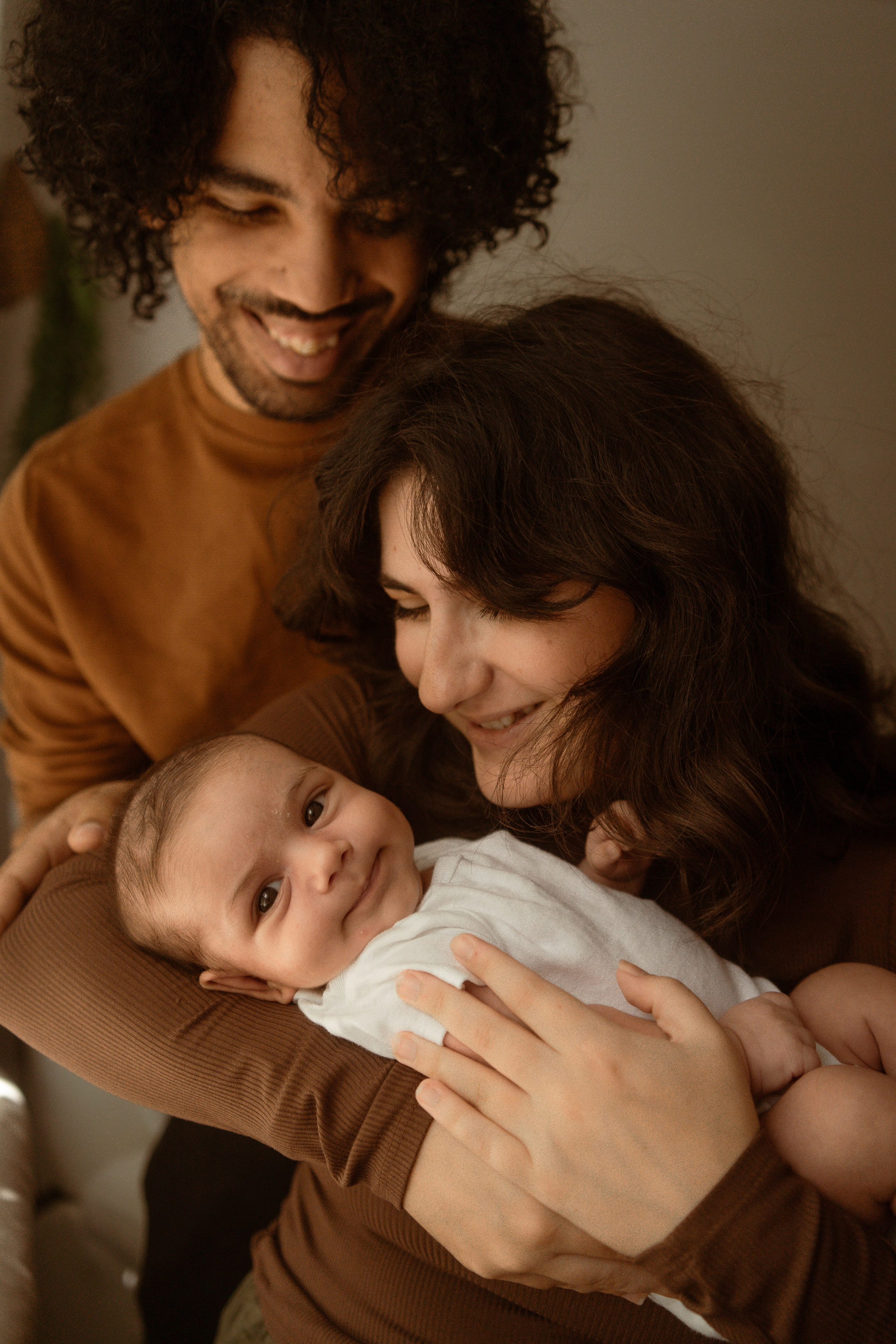 Mother and father holding their newborn together, warm tones
