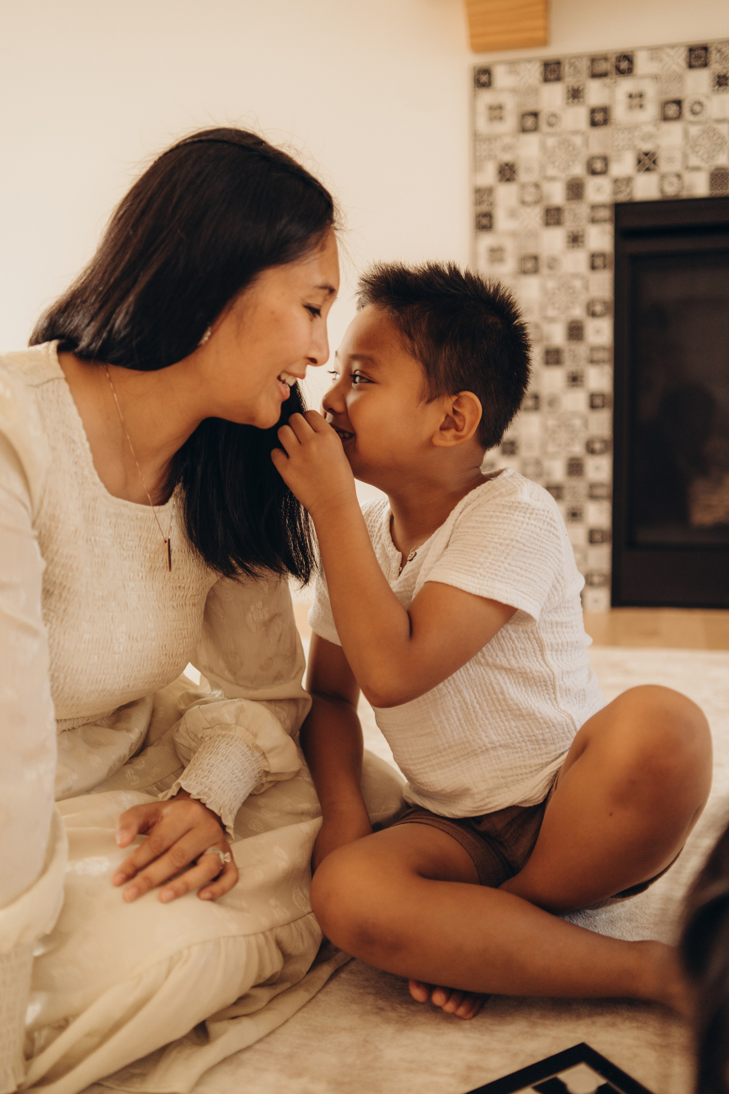 Son leaning in to kiss his mother while they sit on the floor