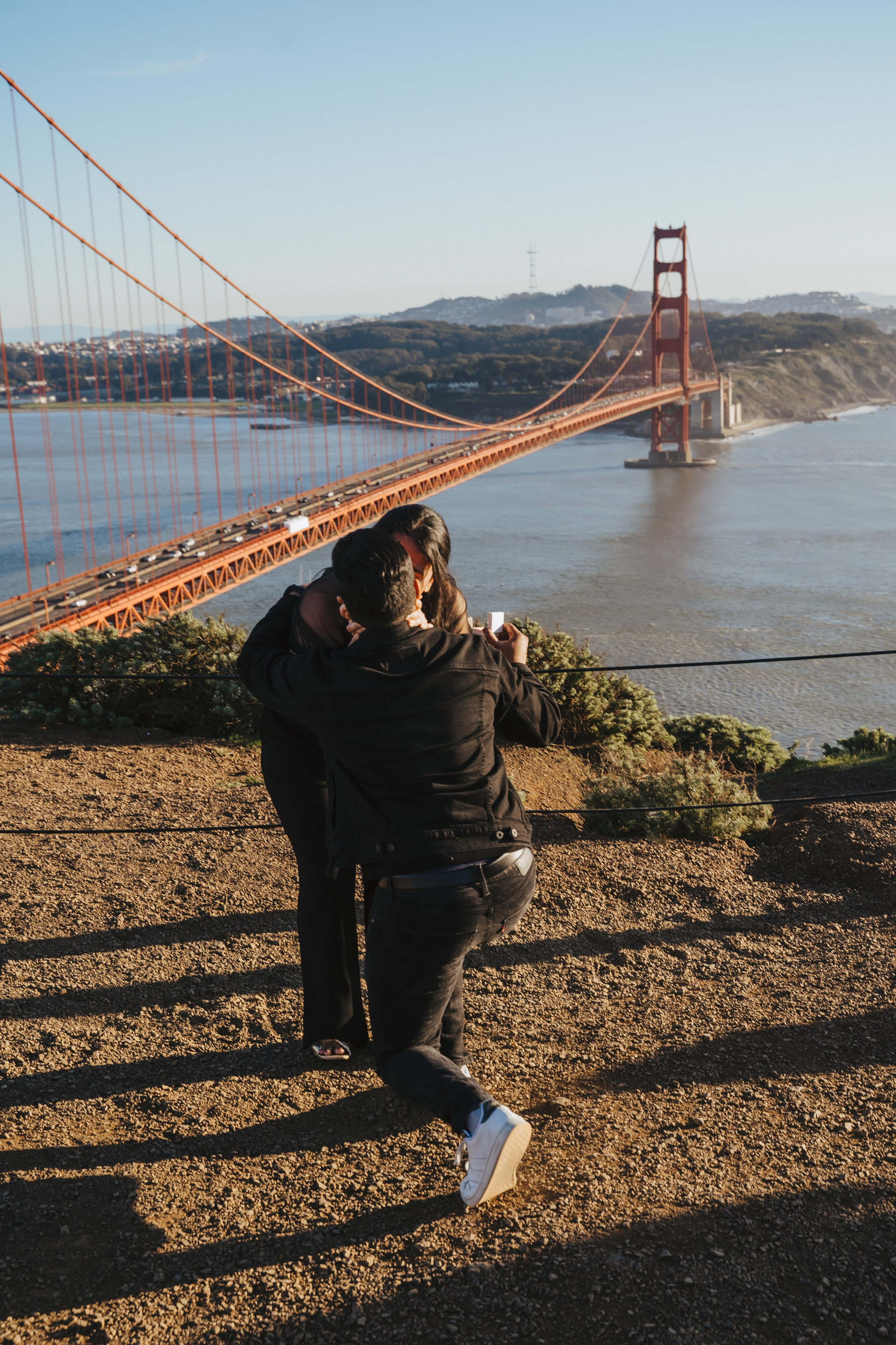 Proposal.  Overlooking the golden San Franisco Bridge sunset with a couple. Photographer Video. 