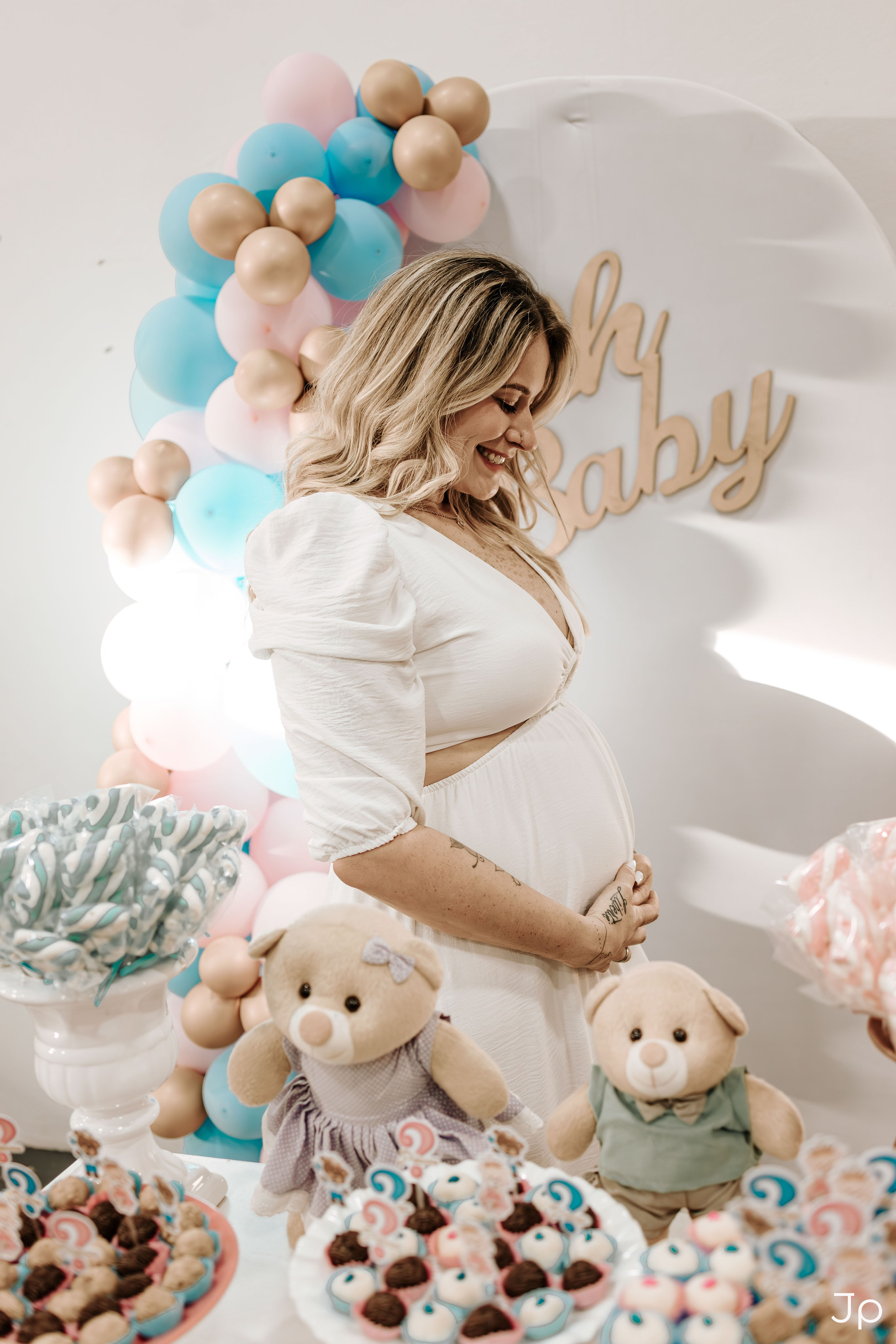 Gestante acaricia a barriga, com decoração ao fundo.