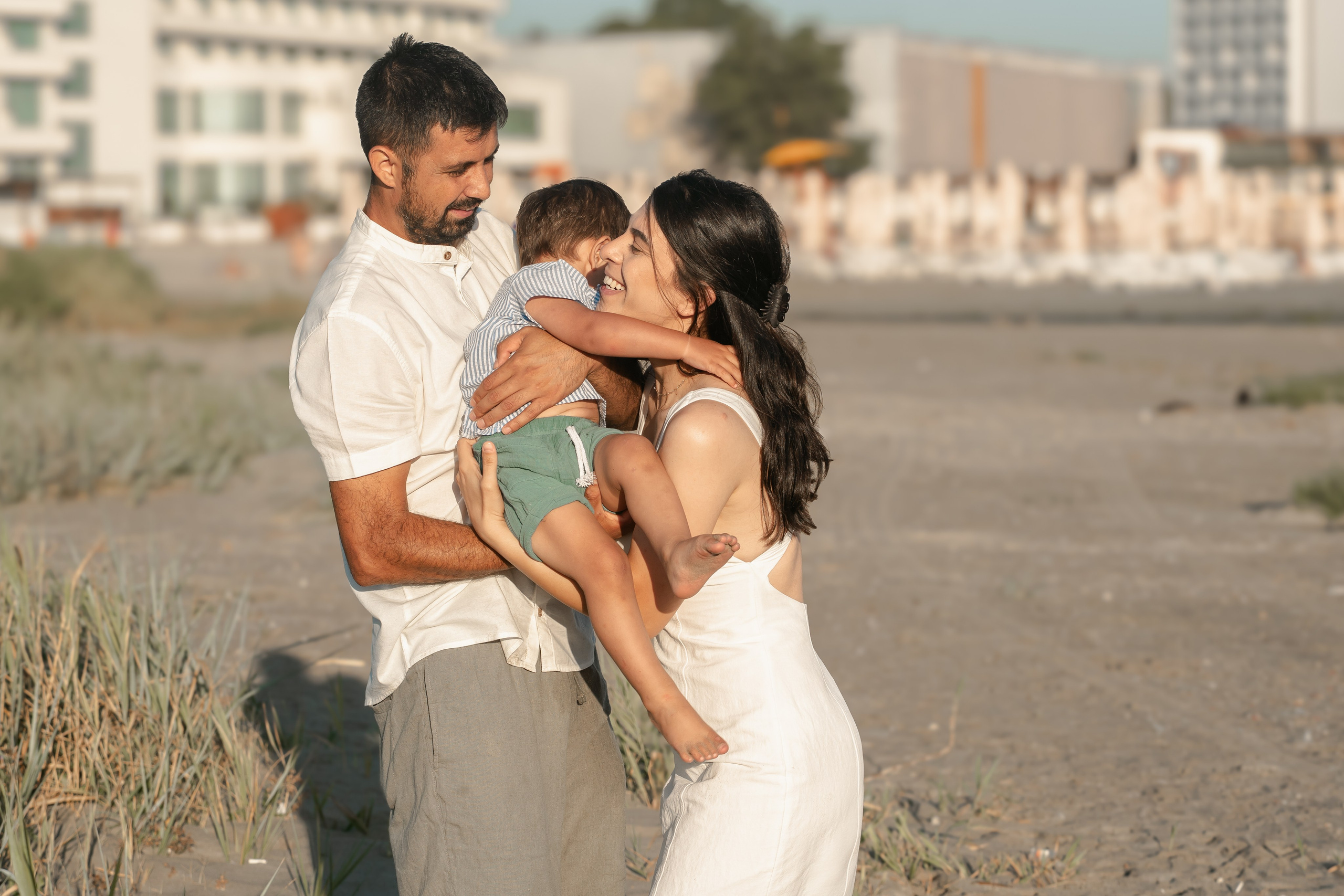 parinti care isi tin copilul in brate pe plaja