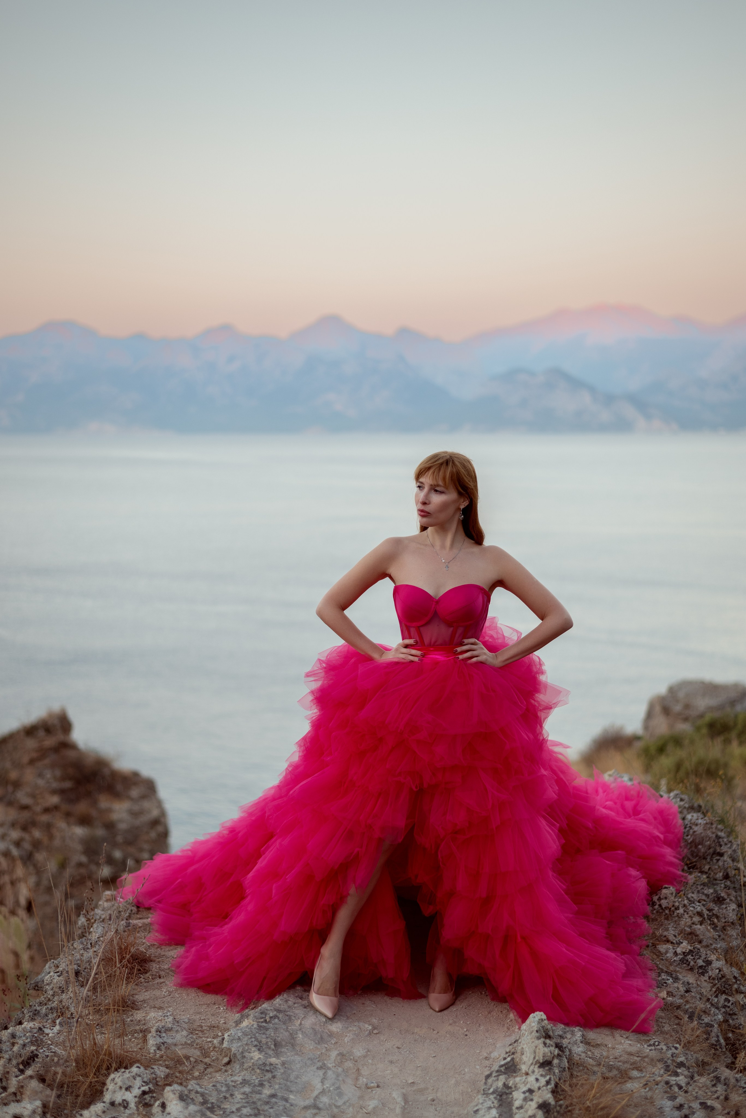 Фотосессия девушки в платье со шлейфом на скалах с видом на море в Анталии