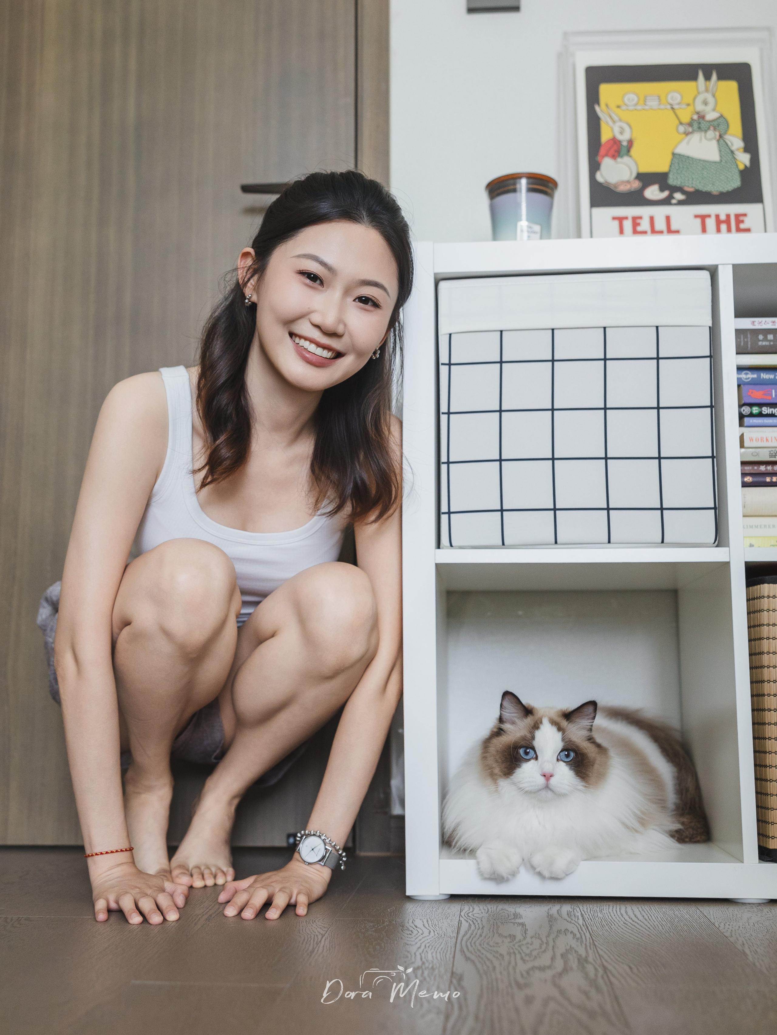 A woman crouches beside her ragdoll cat who sits inside a white cube shelf — a playful and stylish capture by a Shanghai lifestyle photographer.