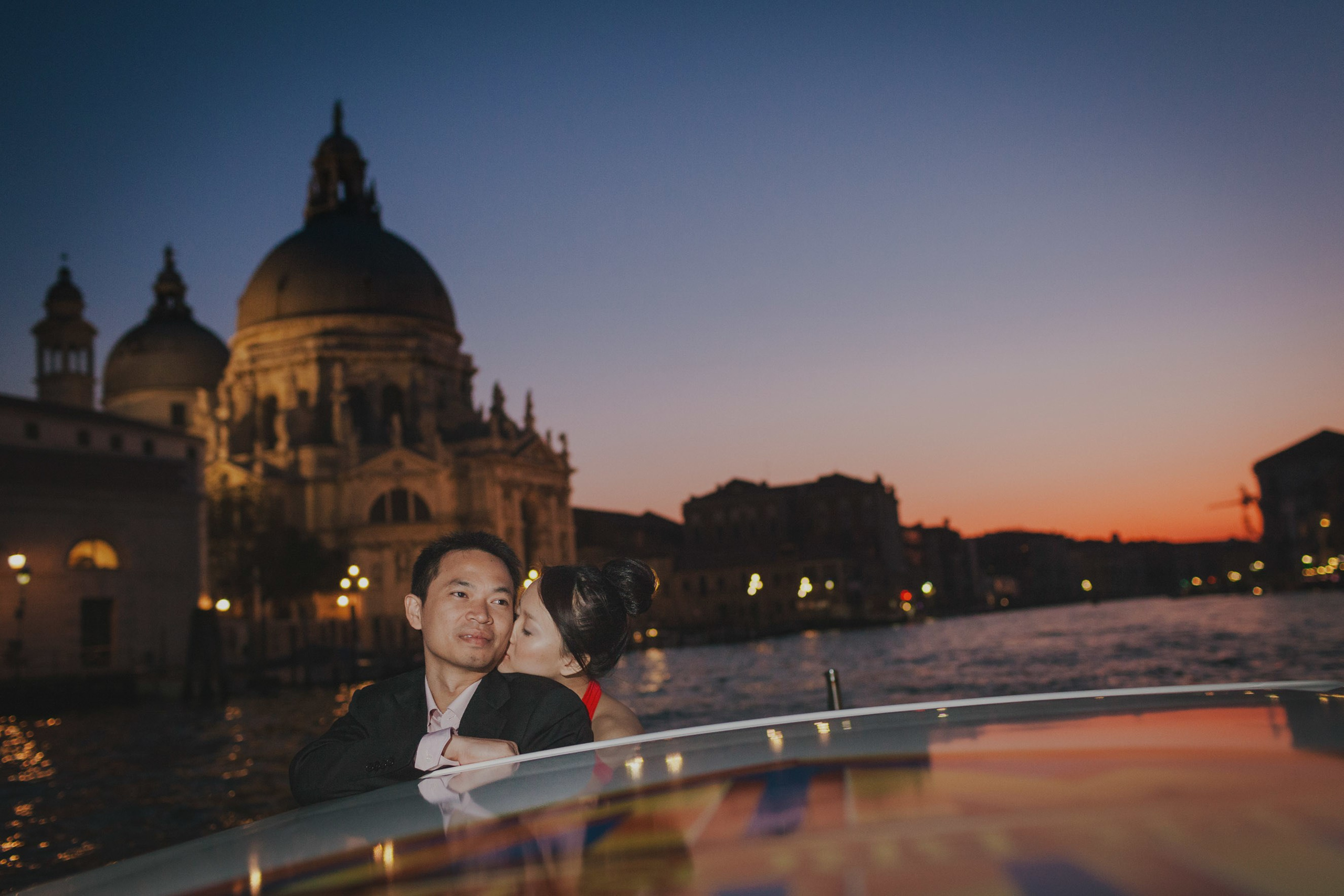 Young Thai couple snuggling during private tour boat ride on Venice waterways.
