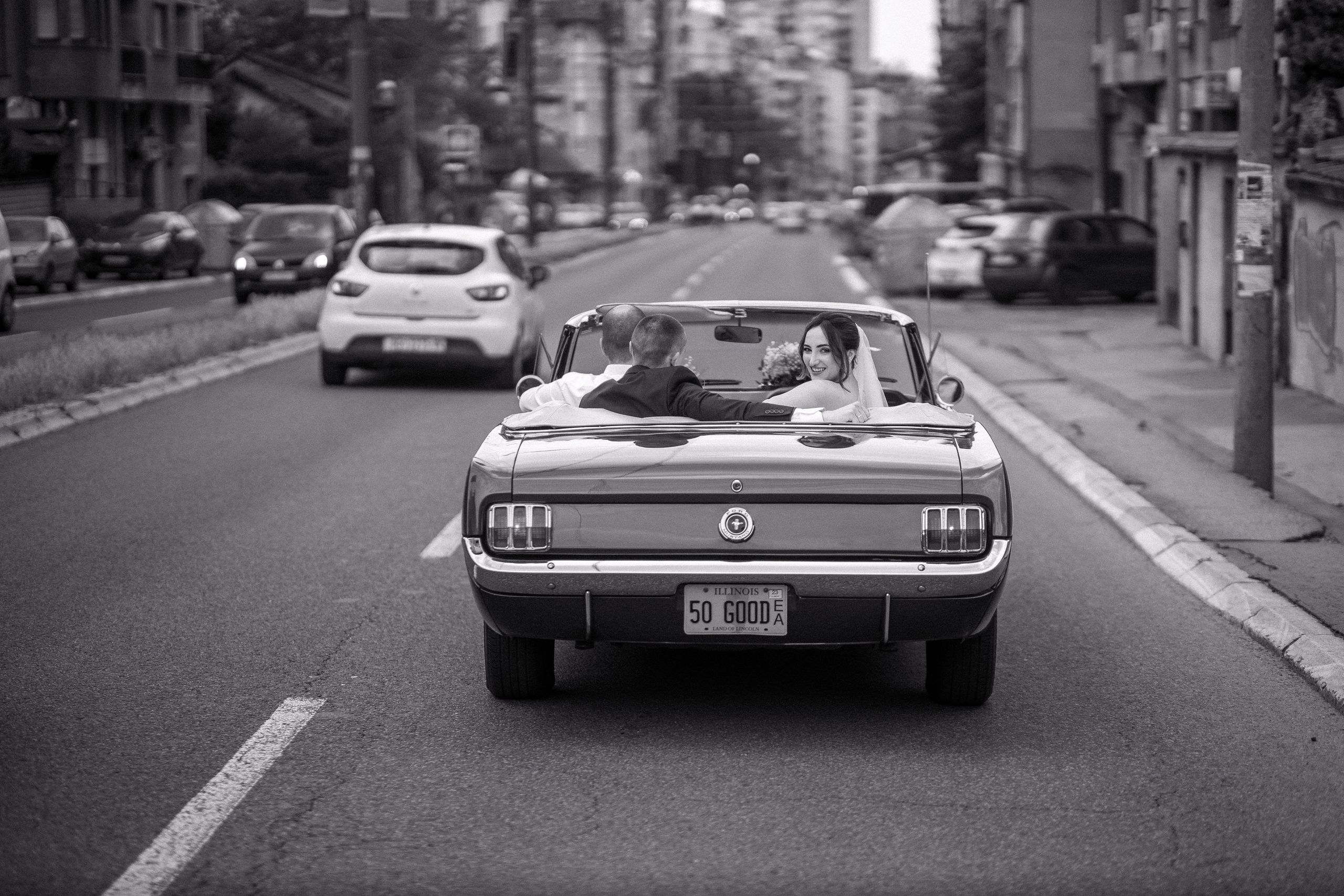 mladenci u retro automobilu voze se kroz grad