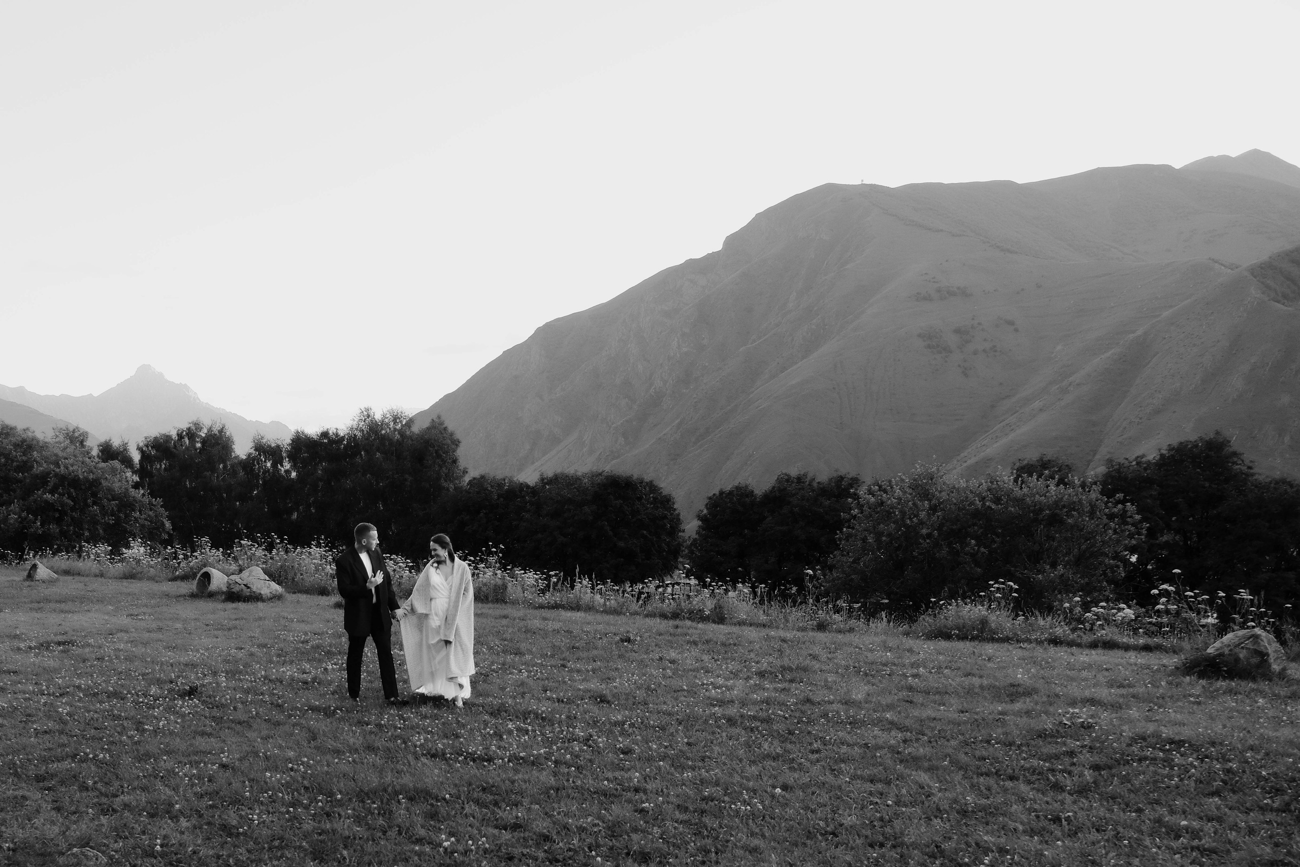 Bride and groom walking through Kazbegi mountain landscape