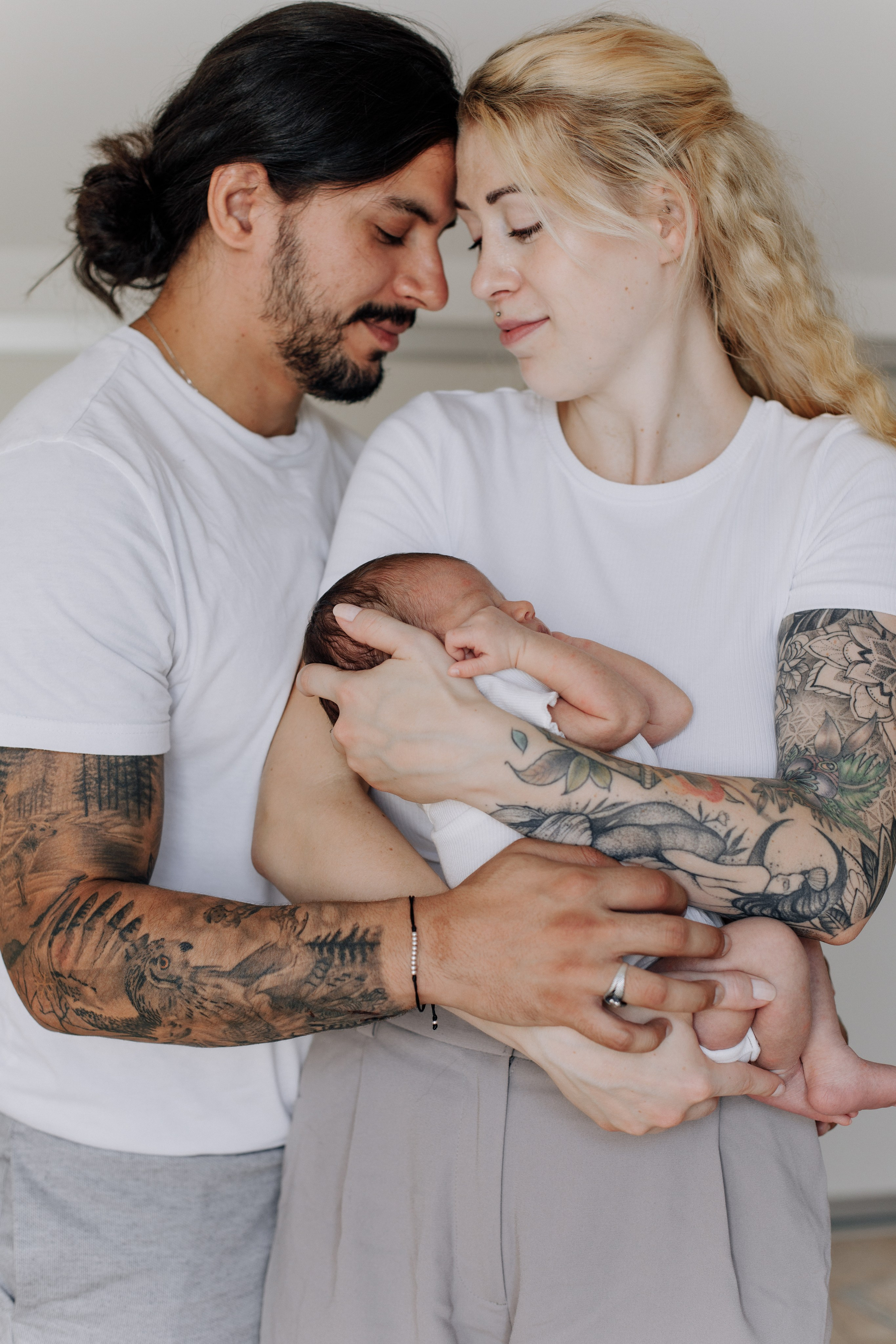 Mann umarmt seine Frau, die ihr Baby im Arm hält.