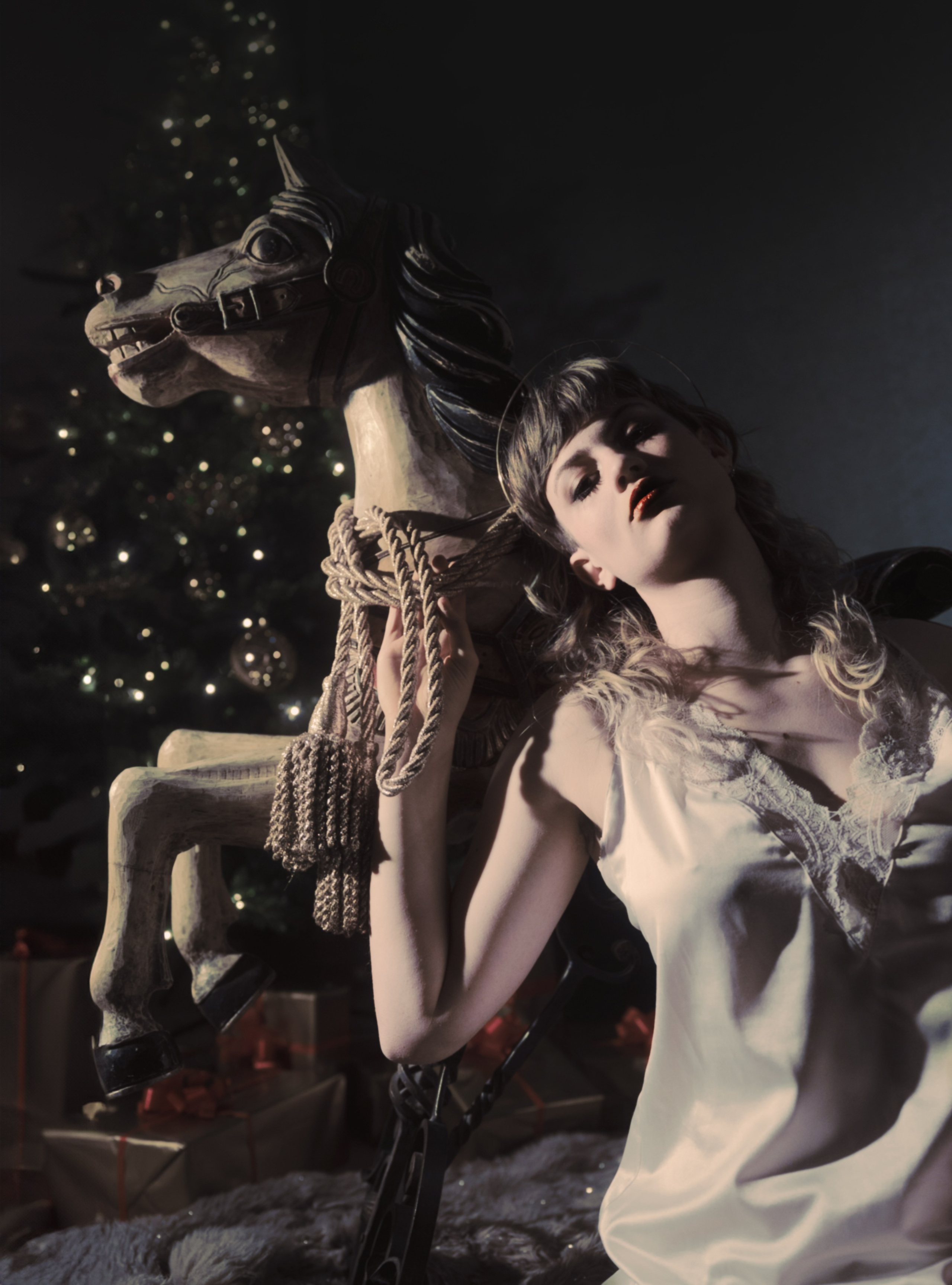 Inszeniertes Portrait einer Schauspielerin – Mädchen und Schaukelpferd in Retro-Inszenierung mit dramatischem Licht