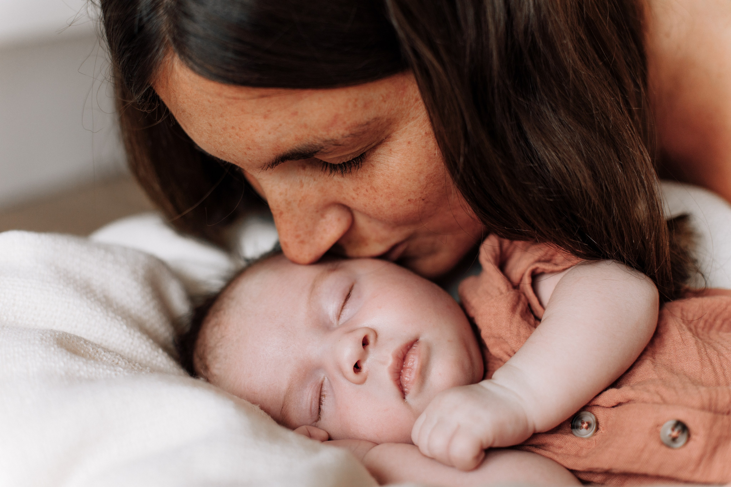 Mutter küsst ihre schlafende Babytochter.