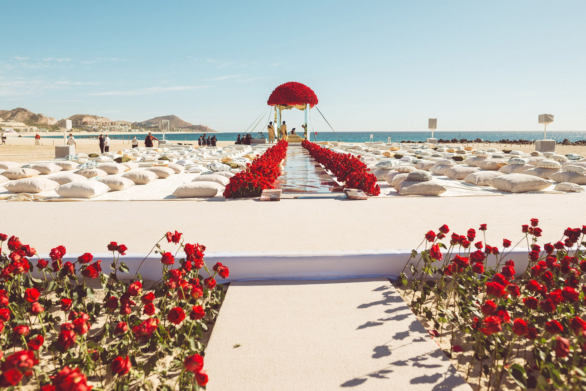 Indian wedding floral decor with red rose aisle and floral mandap dome at oceanfront wedding venue in Los Cabos Mexico