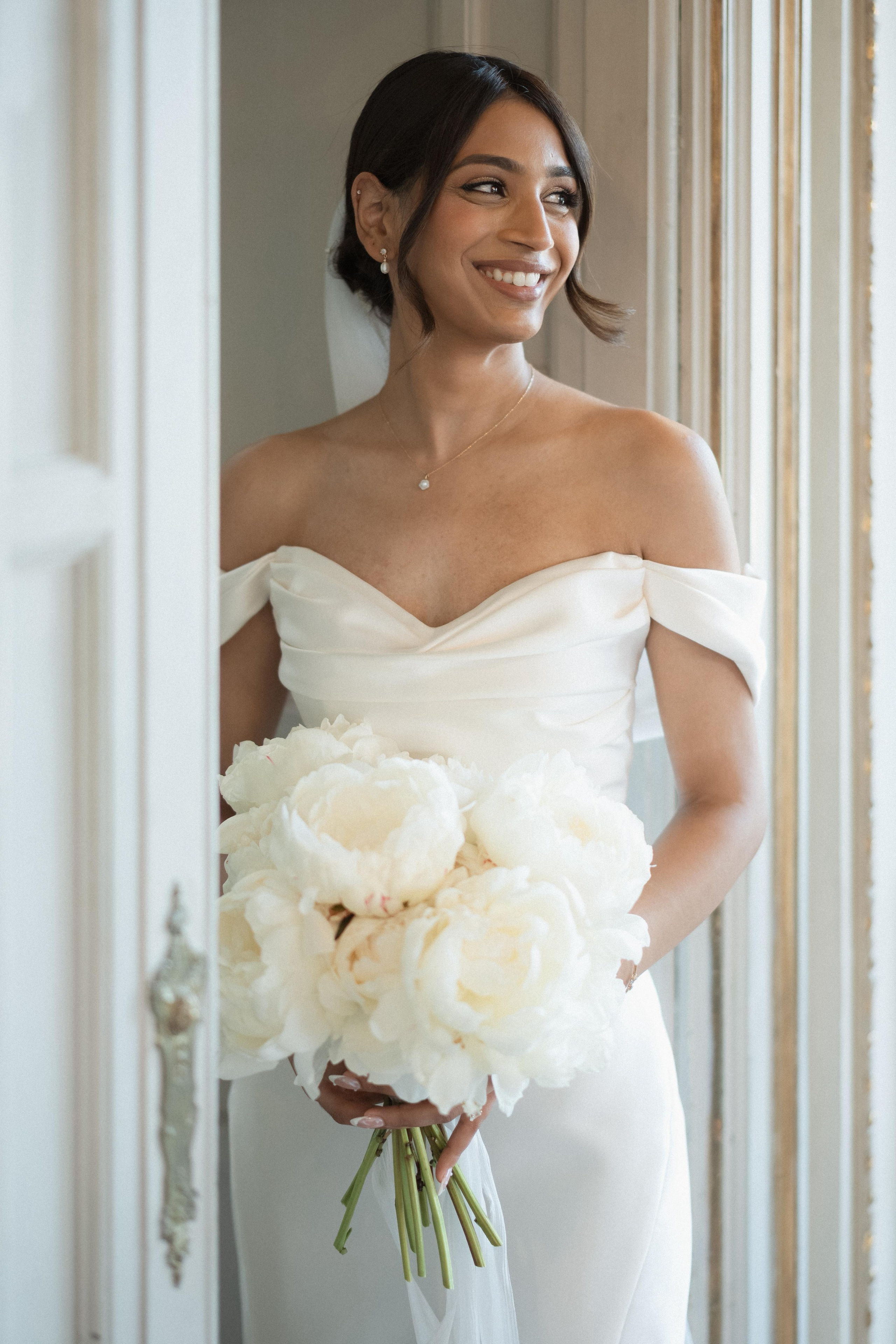 indian bride smiles softly looking outside in a white ambient
