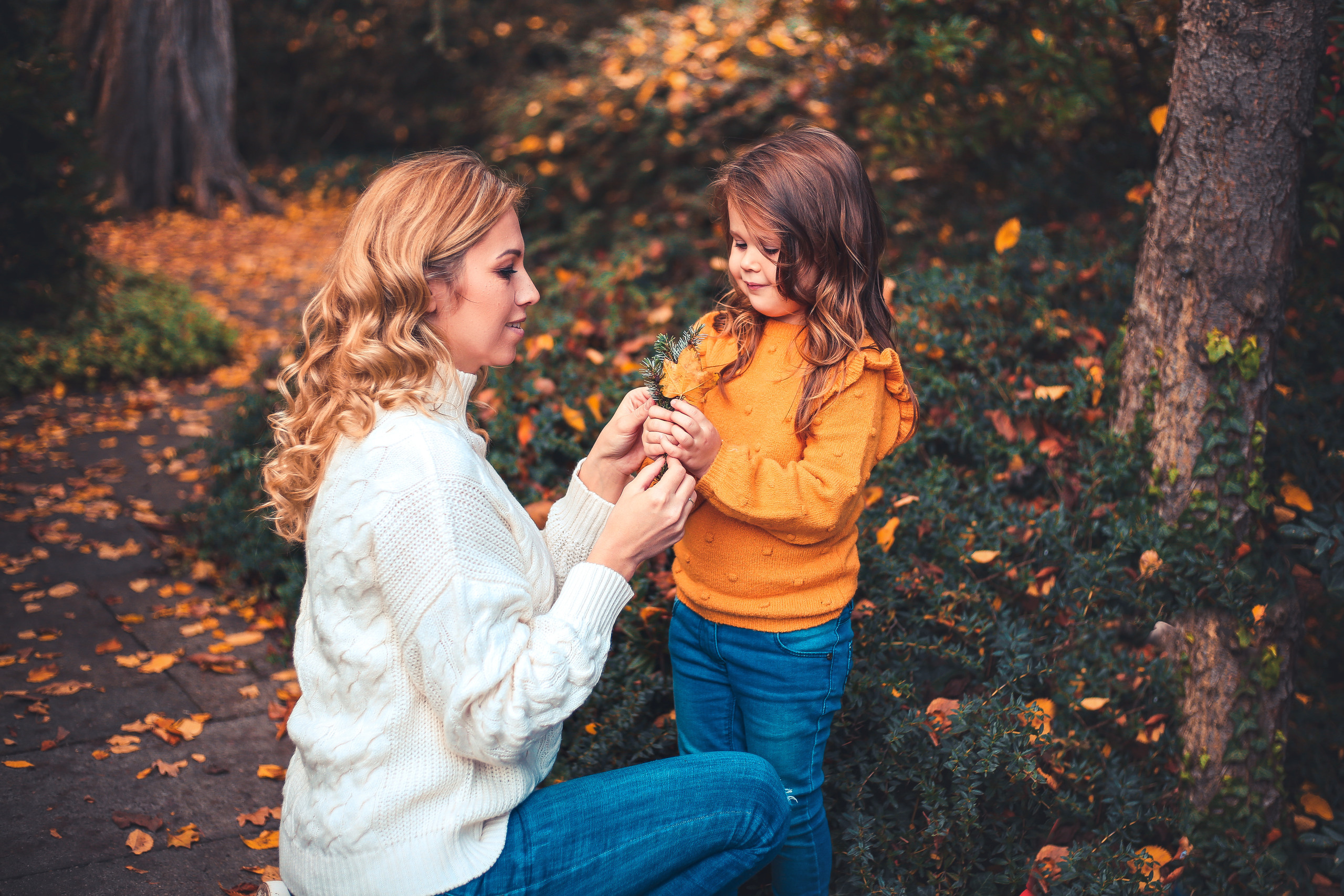 Mama mit Tochter im Park gucken herbstliche Blätter an