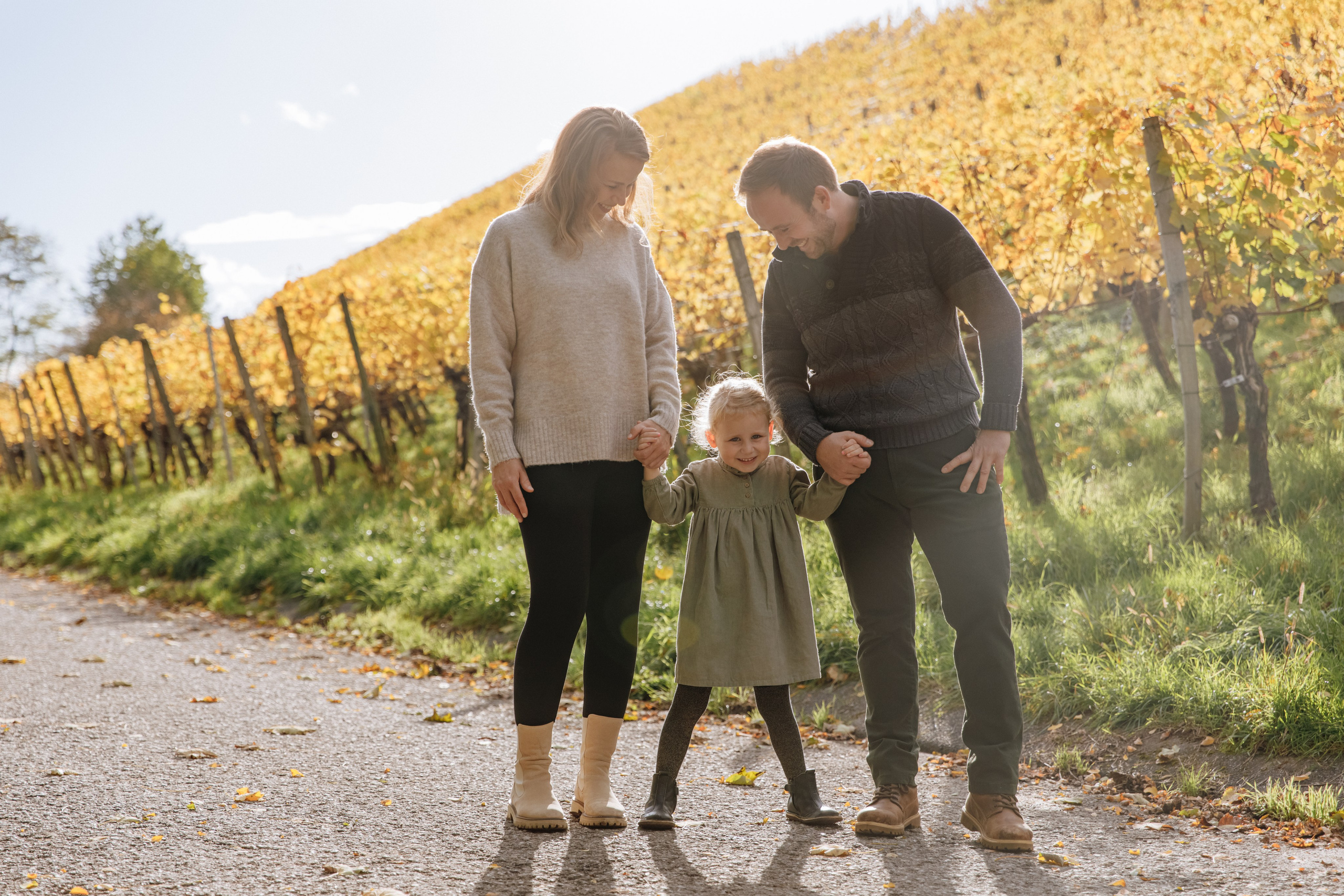 Familie während eines herbstlichen Fotoshootings im Weinberg – warmes Licht und liebevolle Stimmung.