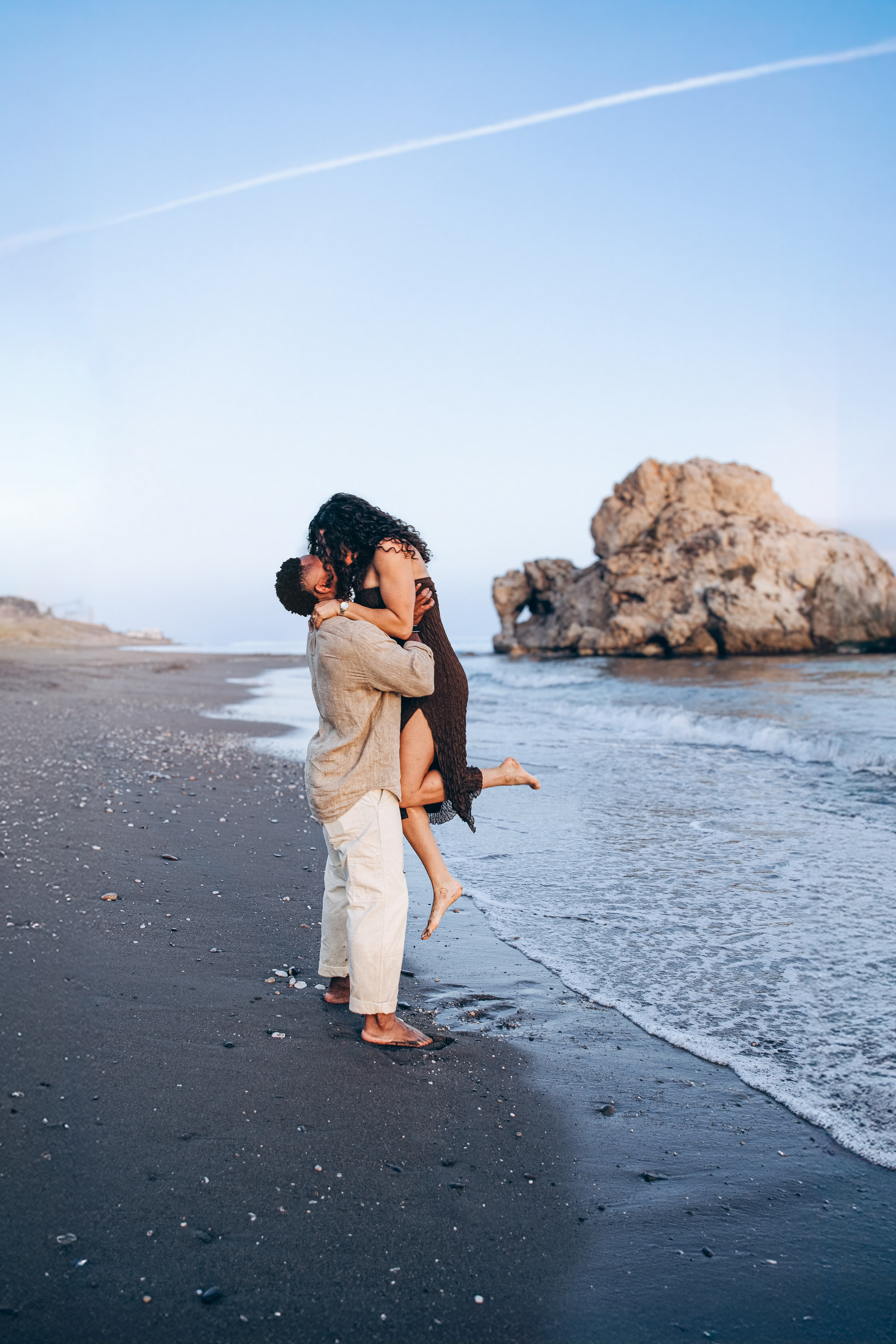 Romantic proposal moment on a Málaga beach with the Mediterranean Sea in the background. Destination engagement session in southern Spain capturing an intimate seaside love story.