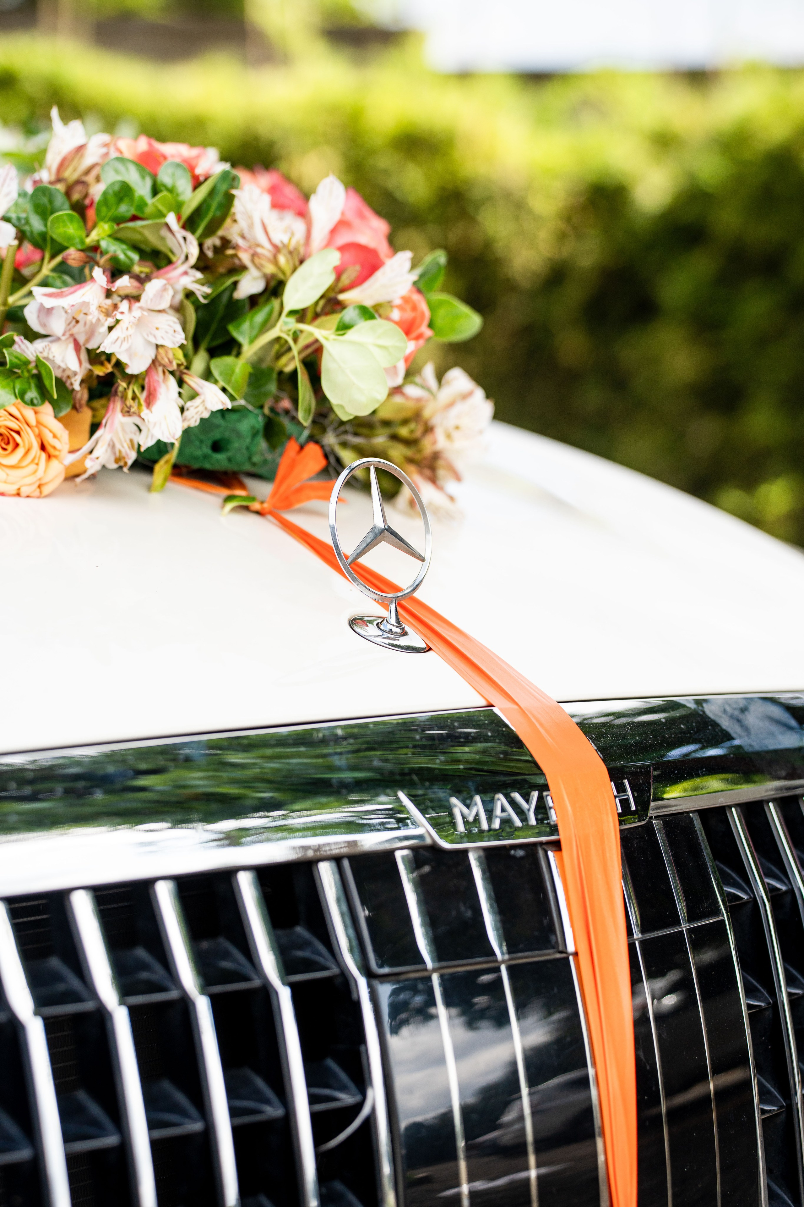An insert shot of a Mercedes Maybach logo decorated with wedding flowers at a wedding in Nairobi