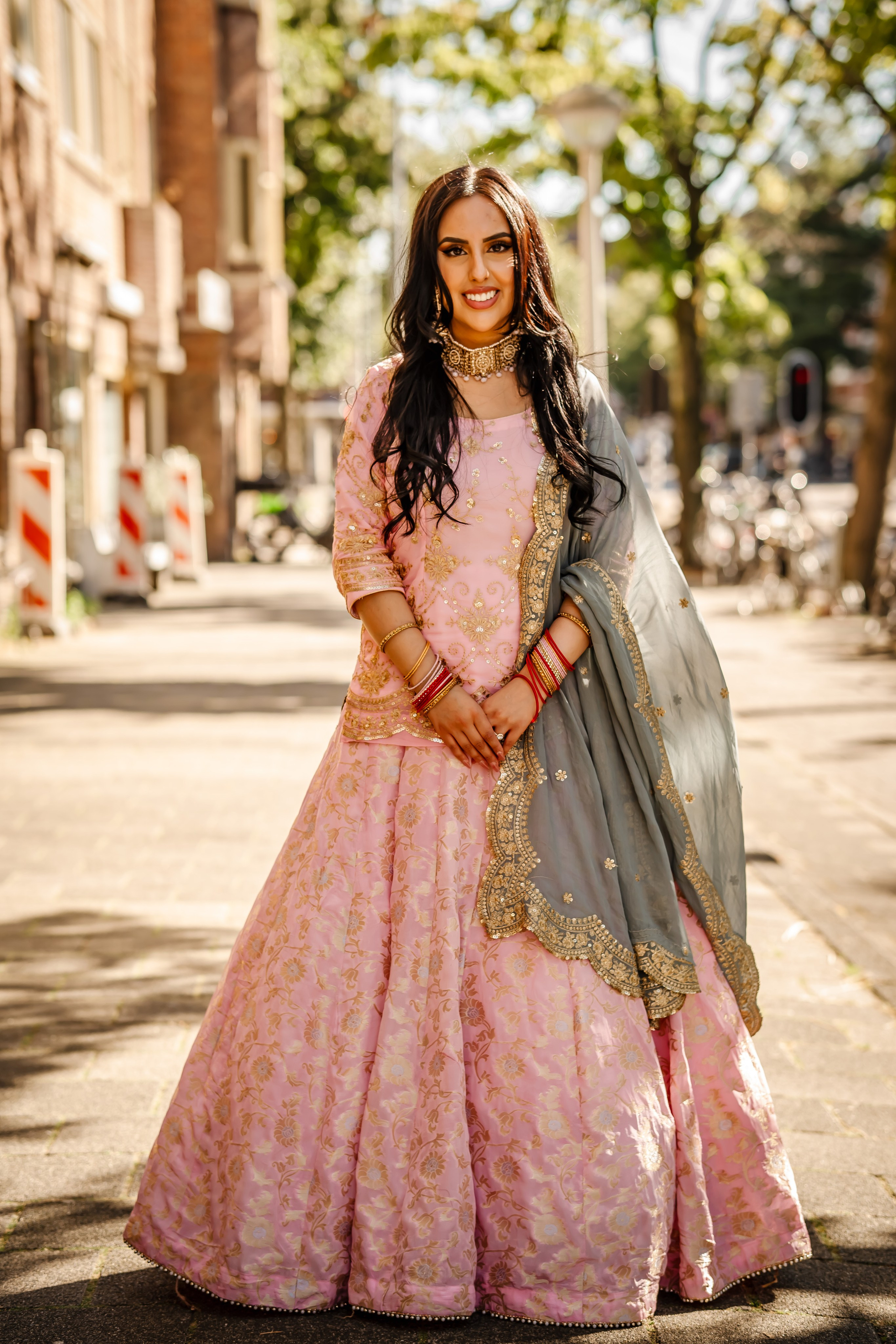 a woman wearing pink bridal lehenga and standing on streets of amsgterdam
