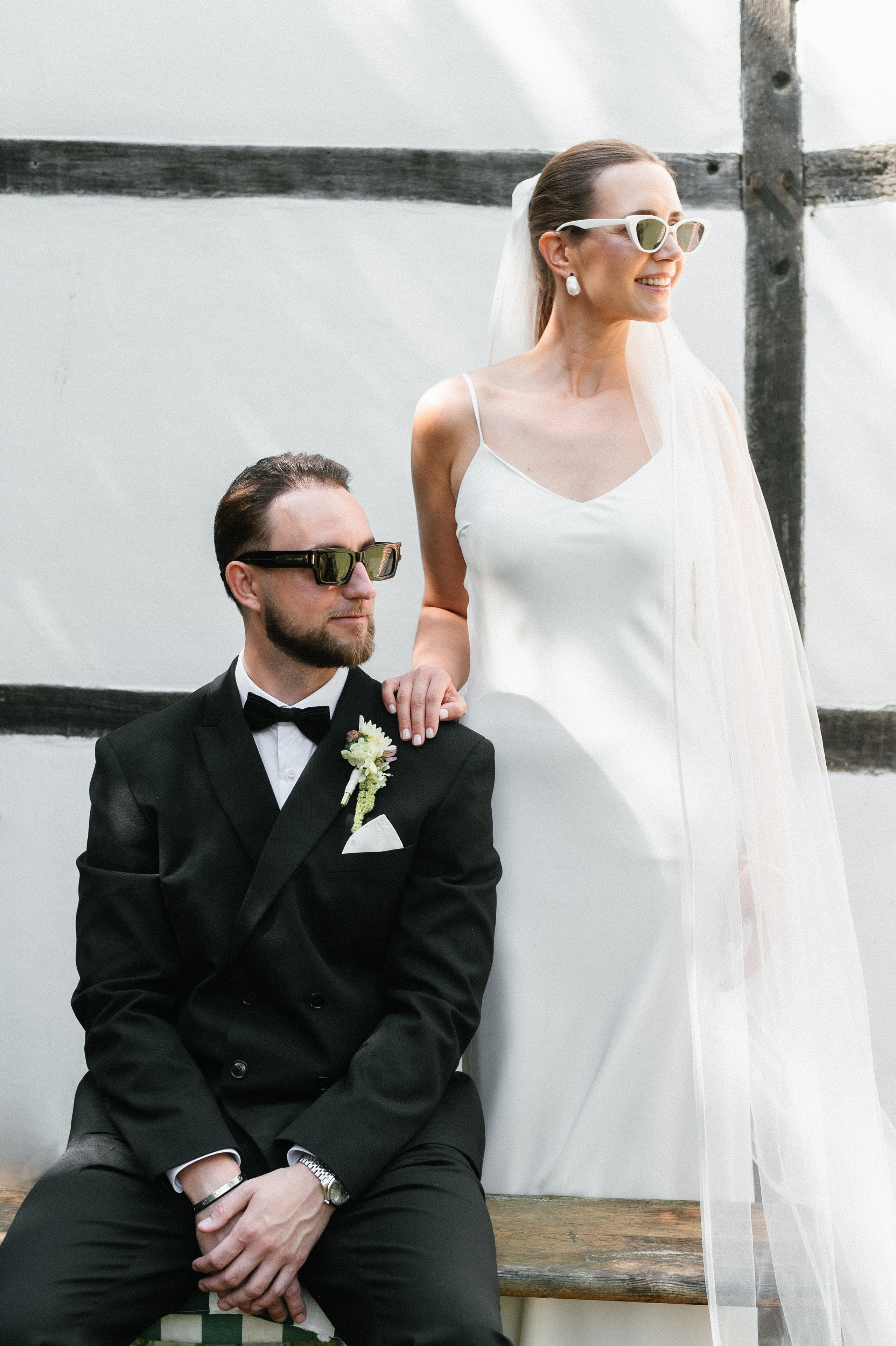 Brautpaar in lockerer Pose mit Sonnenbrillen während des Fotoshootings