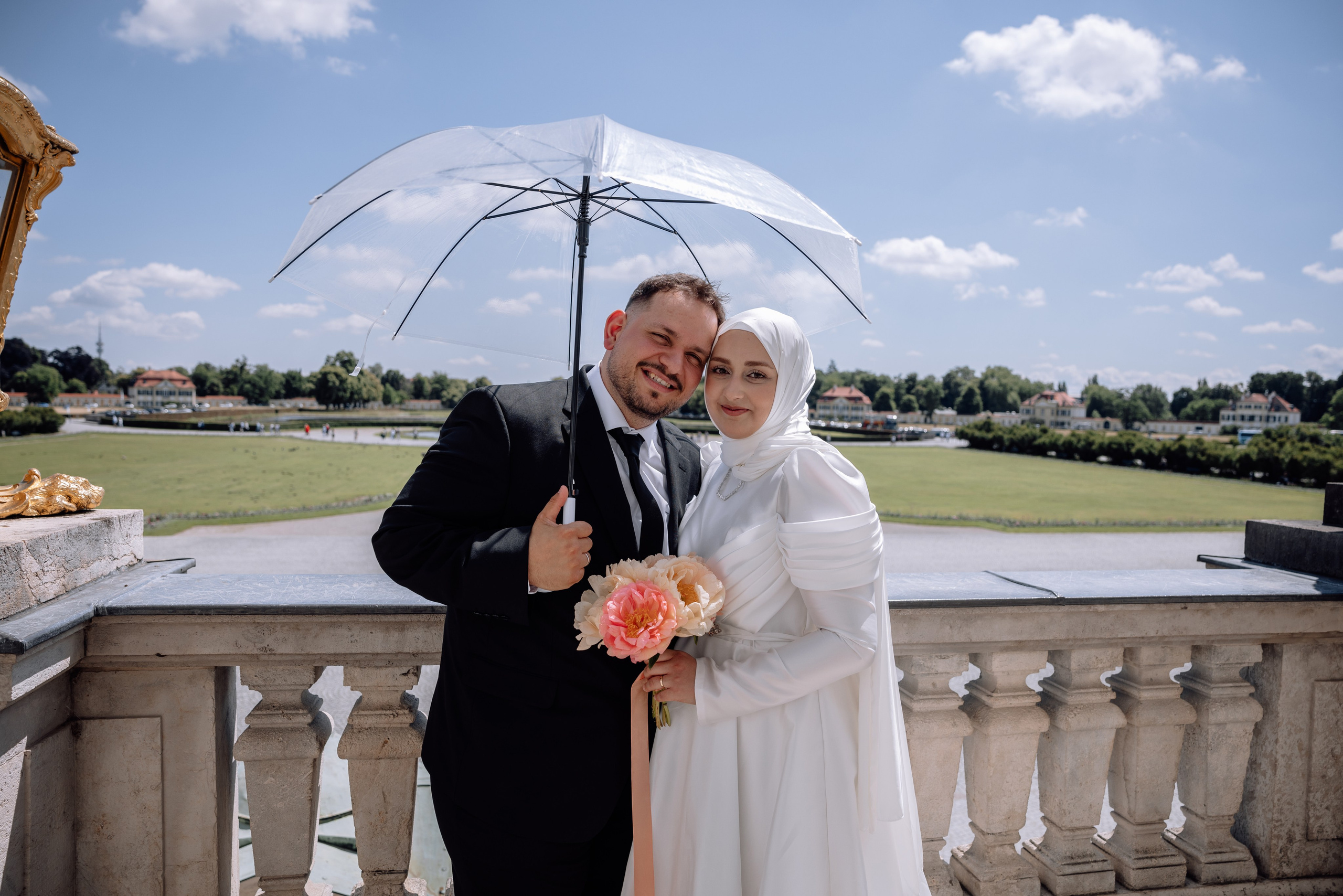 Paar steht unter einem Sonnenschirm vor dem Schloss Nymphenburg