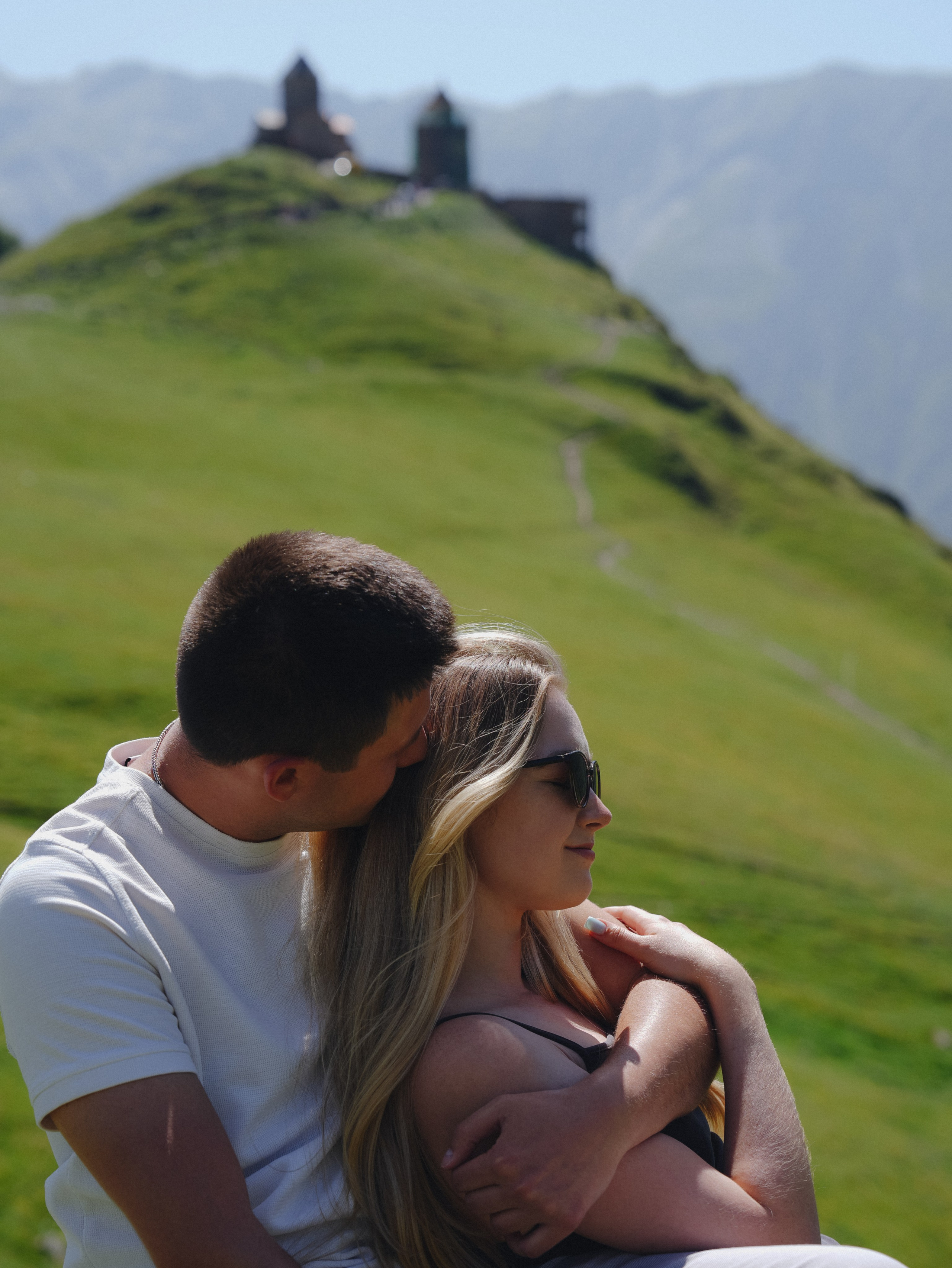Couple sitting near Gergeti church scenic view