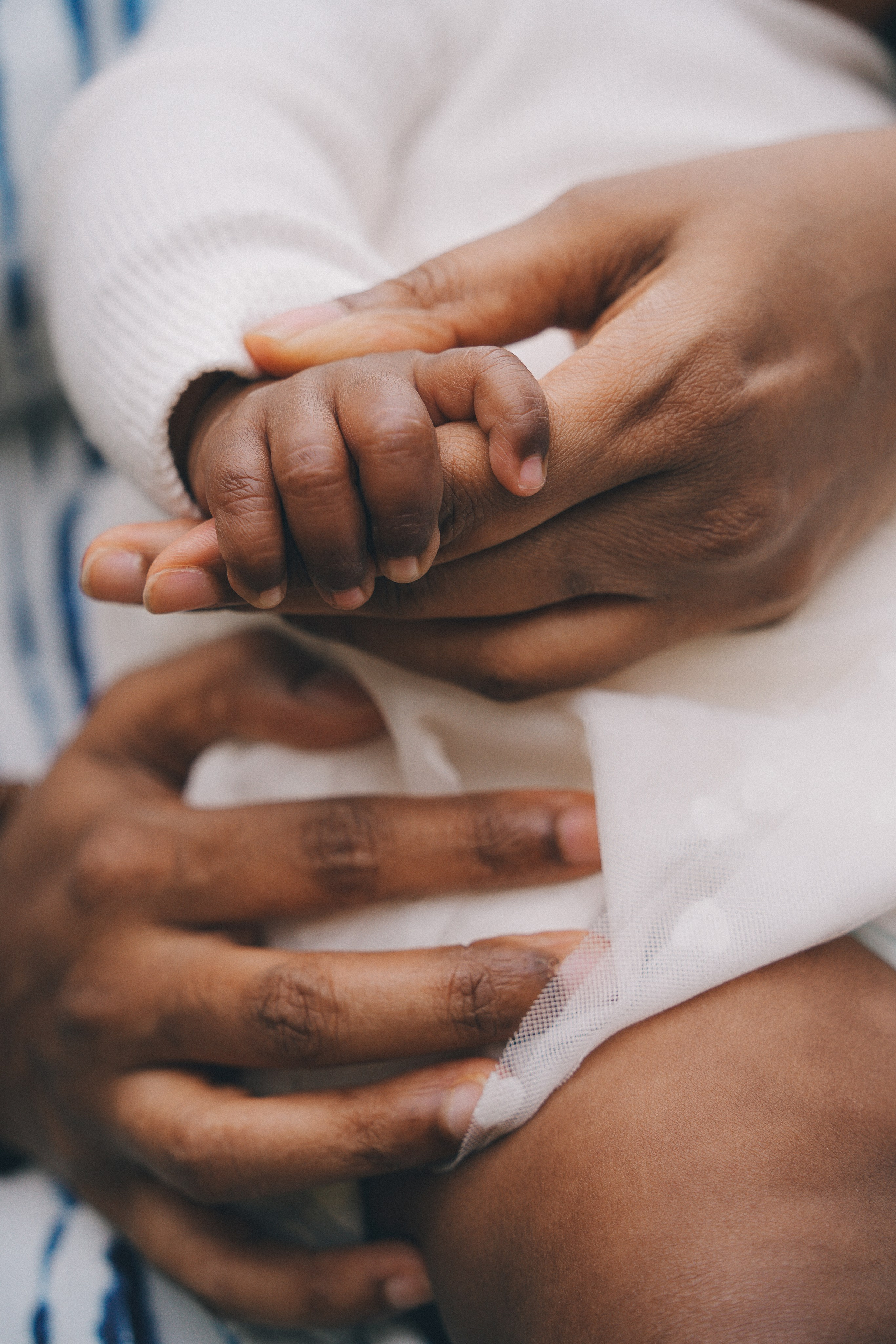 Close up of parents’ hands holding a newborn baby during an at home family session, Solihull