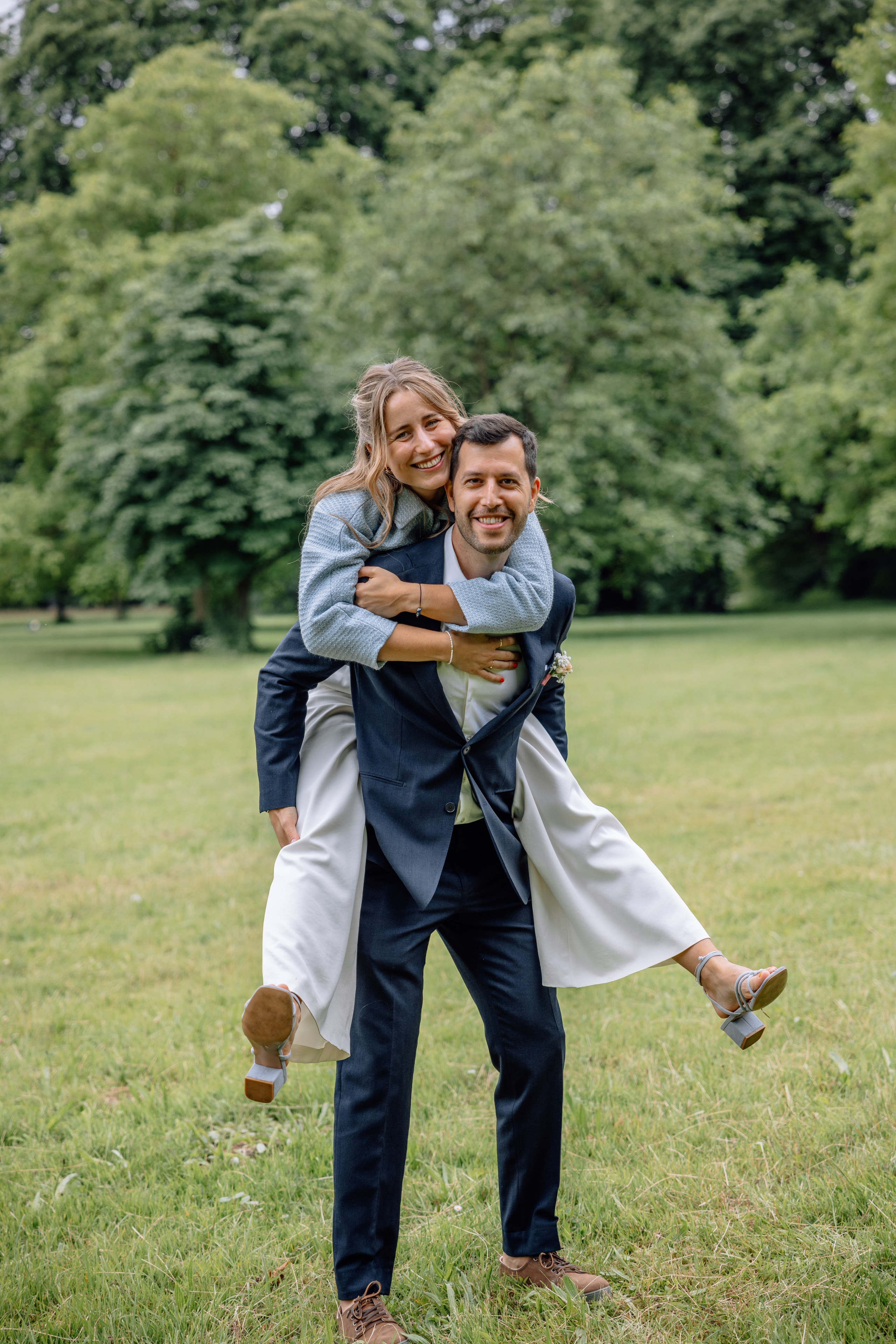 Braut auf dem Rücken des Bräutigams getragen, Standesamt Schwabing im Hintergrund