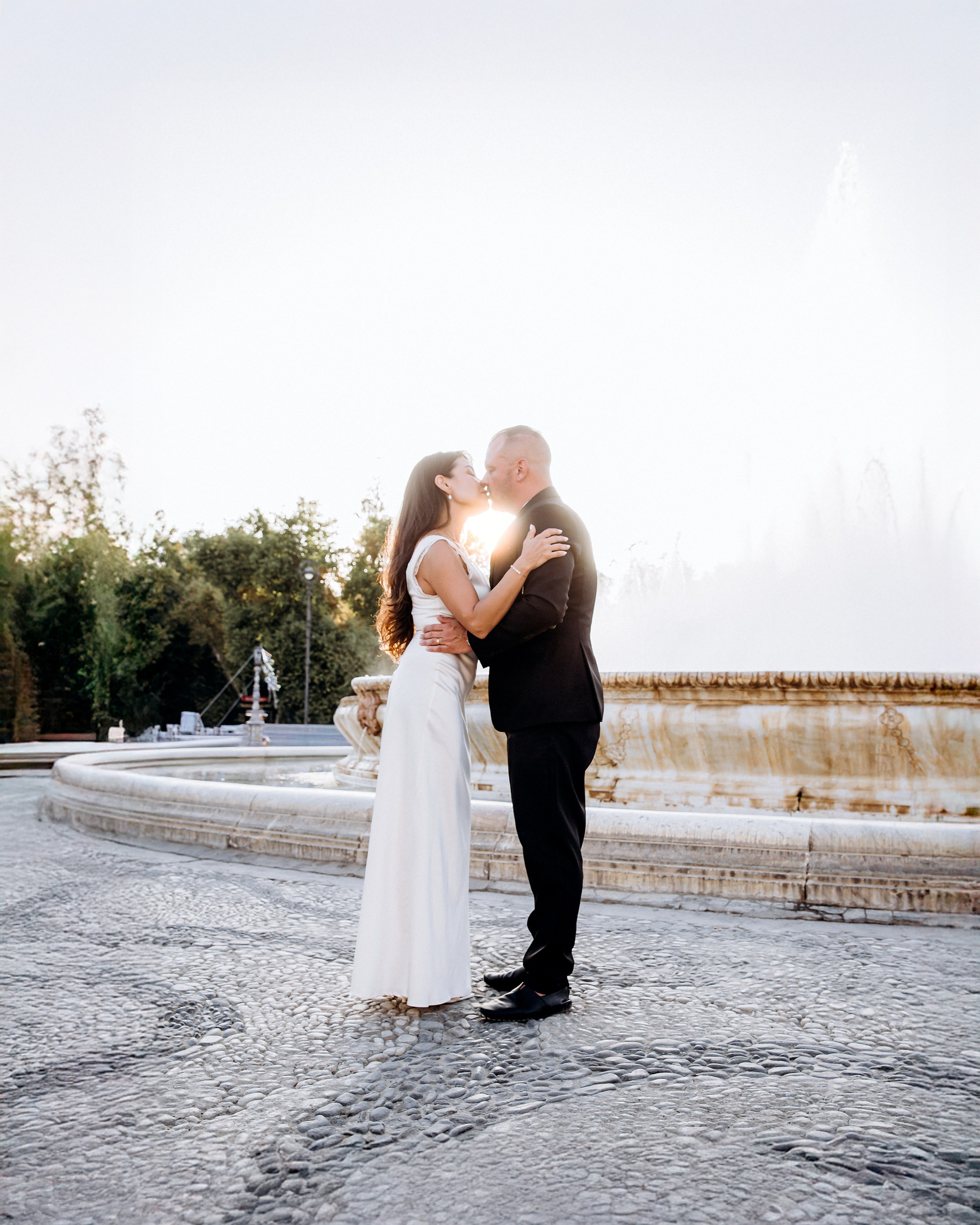 Romantic wedding kiss captured in front of a serene fountain at sunset in Barcelona, Spain — the couple embraces tenderly in elegant wedding attire. Ideal for couples searching for timeless, emotional, and artistic wedding photoshoots in Barcelona and across Spain.