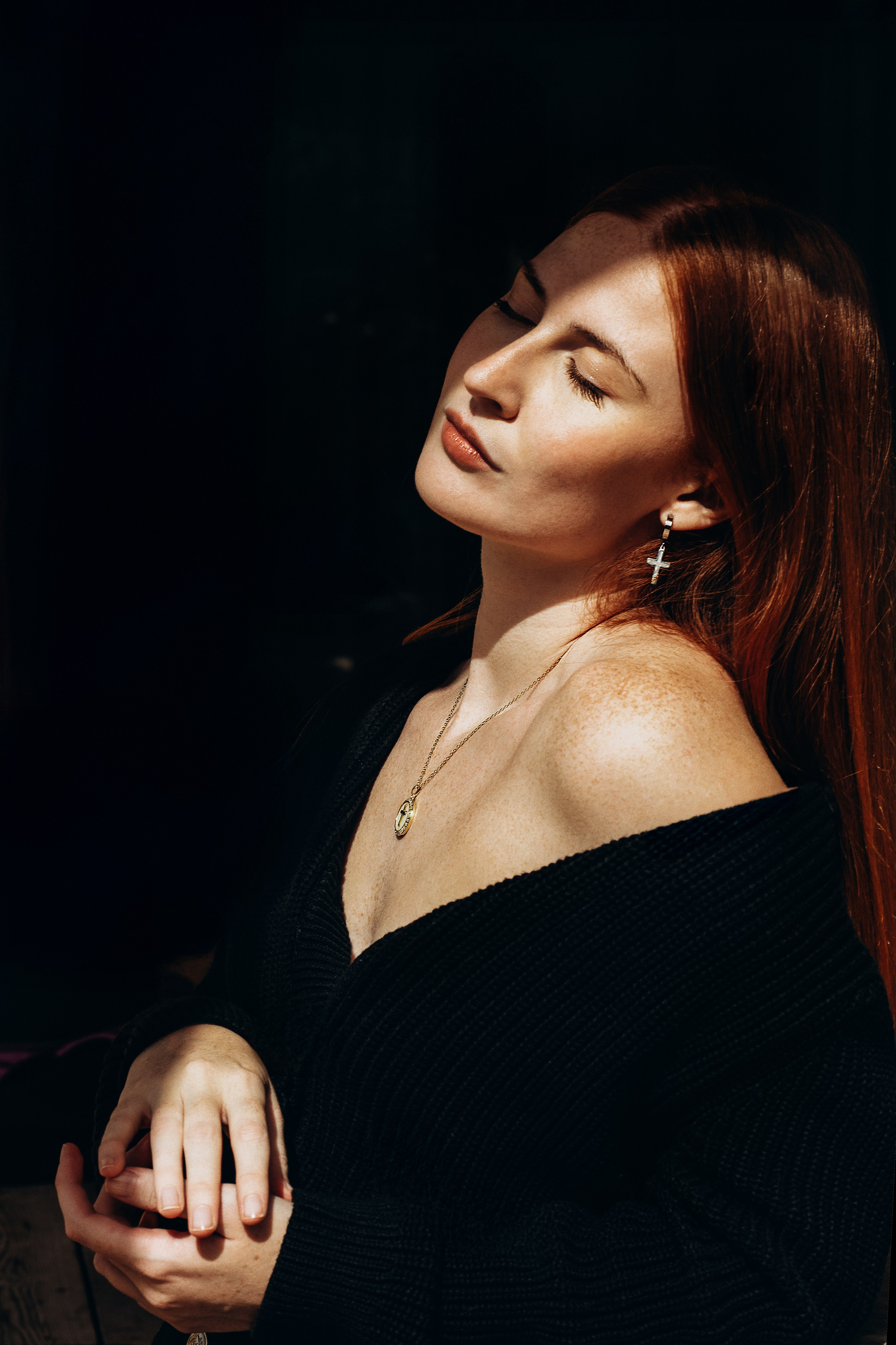 Elegant brand photography captured in Valencia, Spain featuring a red-haired woman in natural light, showcasing minimalist cross earrings and a delicate pendant necklace — ideal for jewelry brands seeking timeless, artistic product photoshoots in Valencia and throughout Spain.