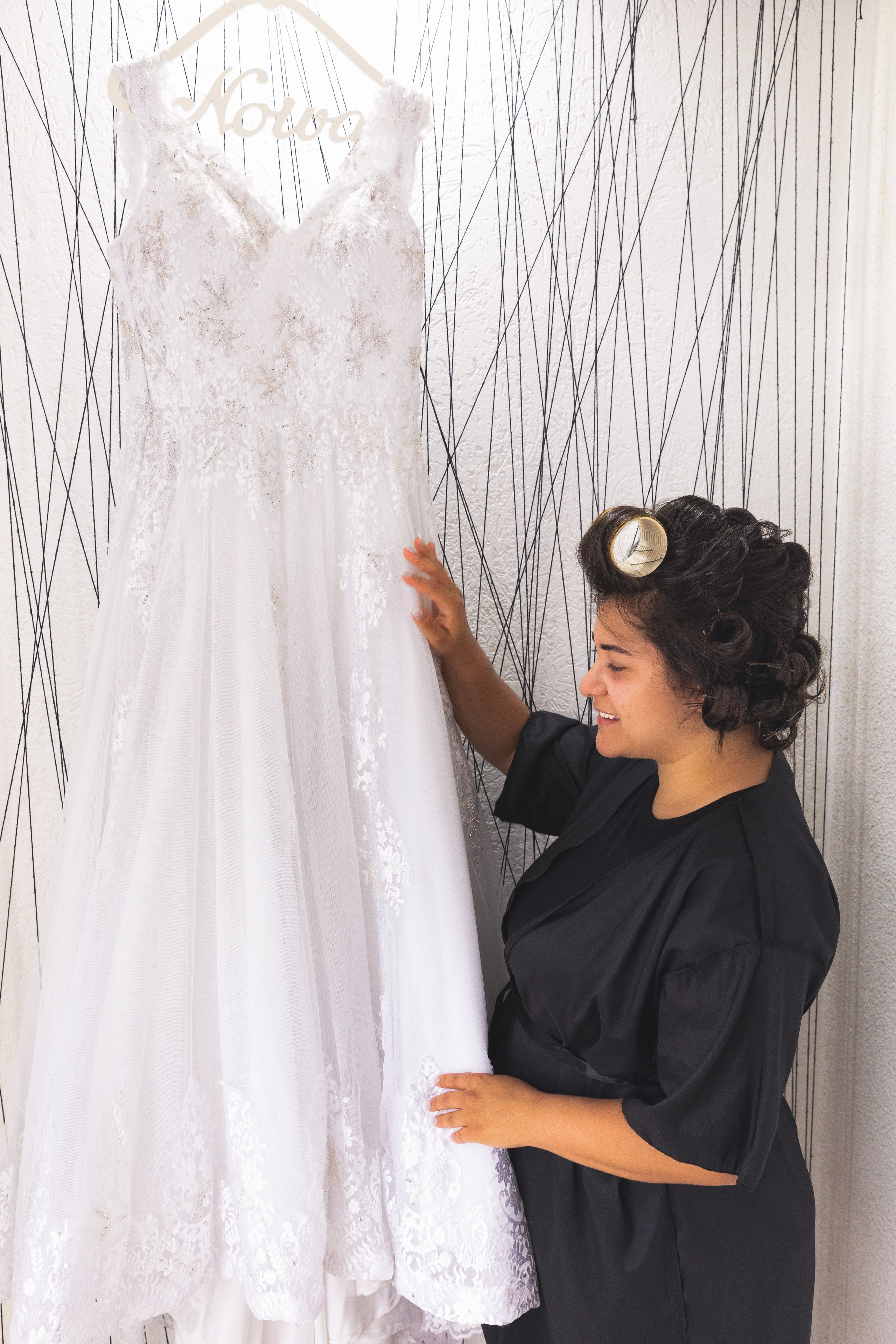 Noiva em seu making-of admirando o seu vestido belíssimo.