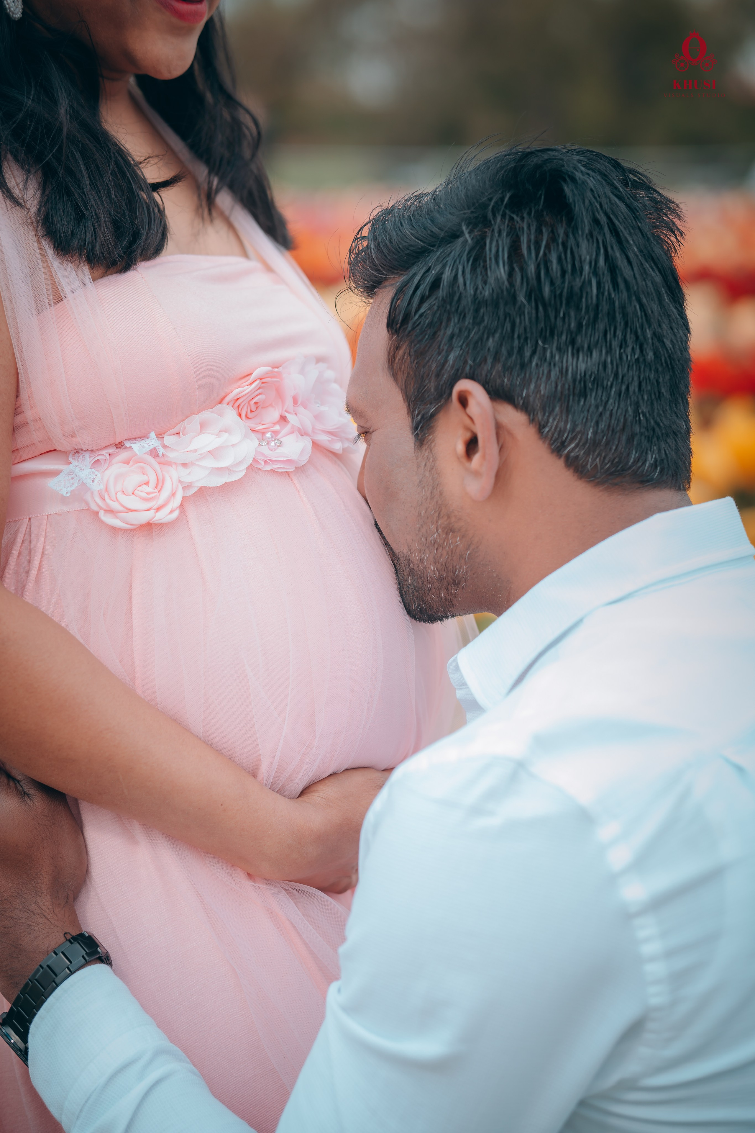 A man kissing the baby bump of his pregnant wife in a tulip fields in netherlands