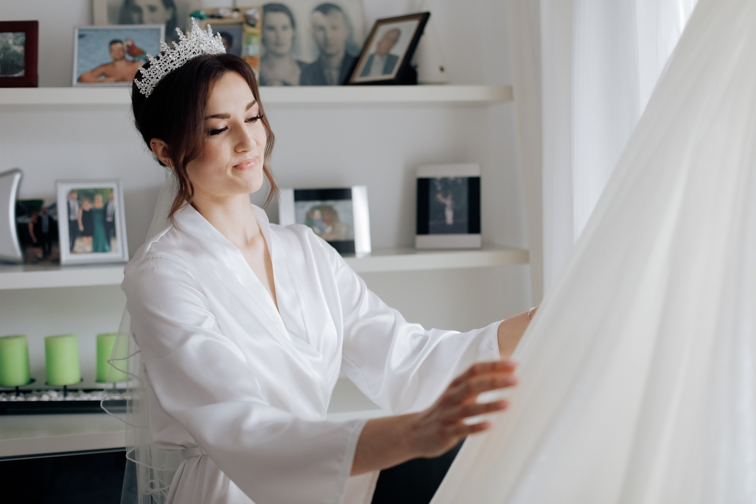 Die Braut schaut auf ihr Hochzeitskleid mit einem verträumten Blick. Ein emotionaler Moment der Vorbereitung.