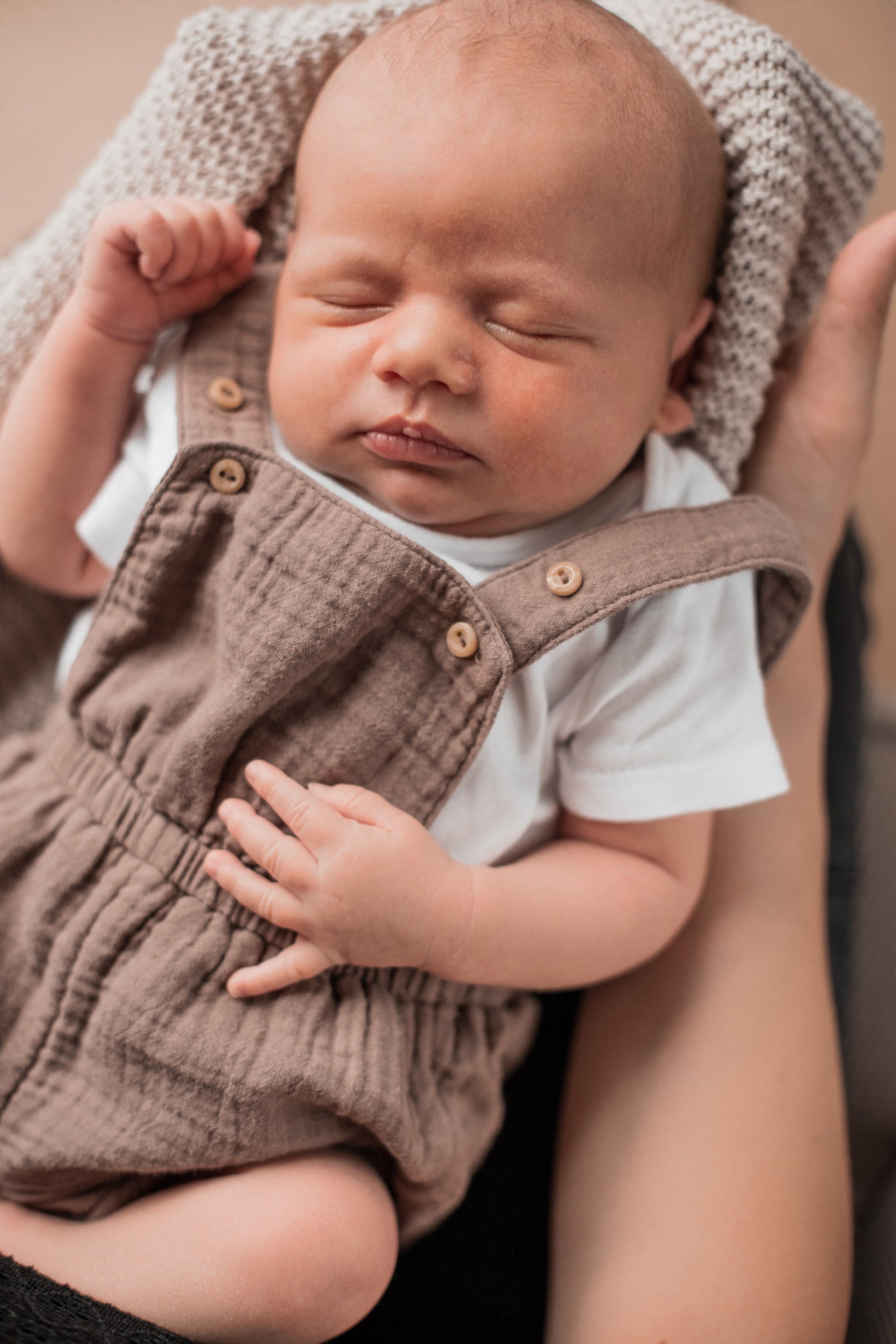 Baby schläft auf den Armen der Eltern.