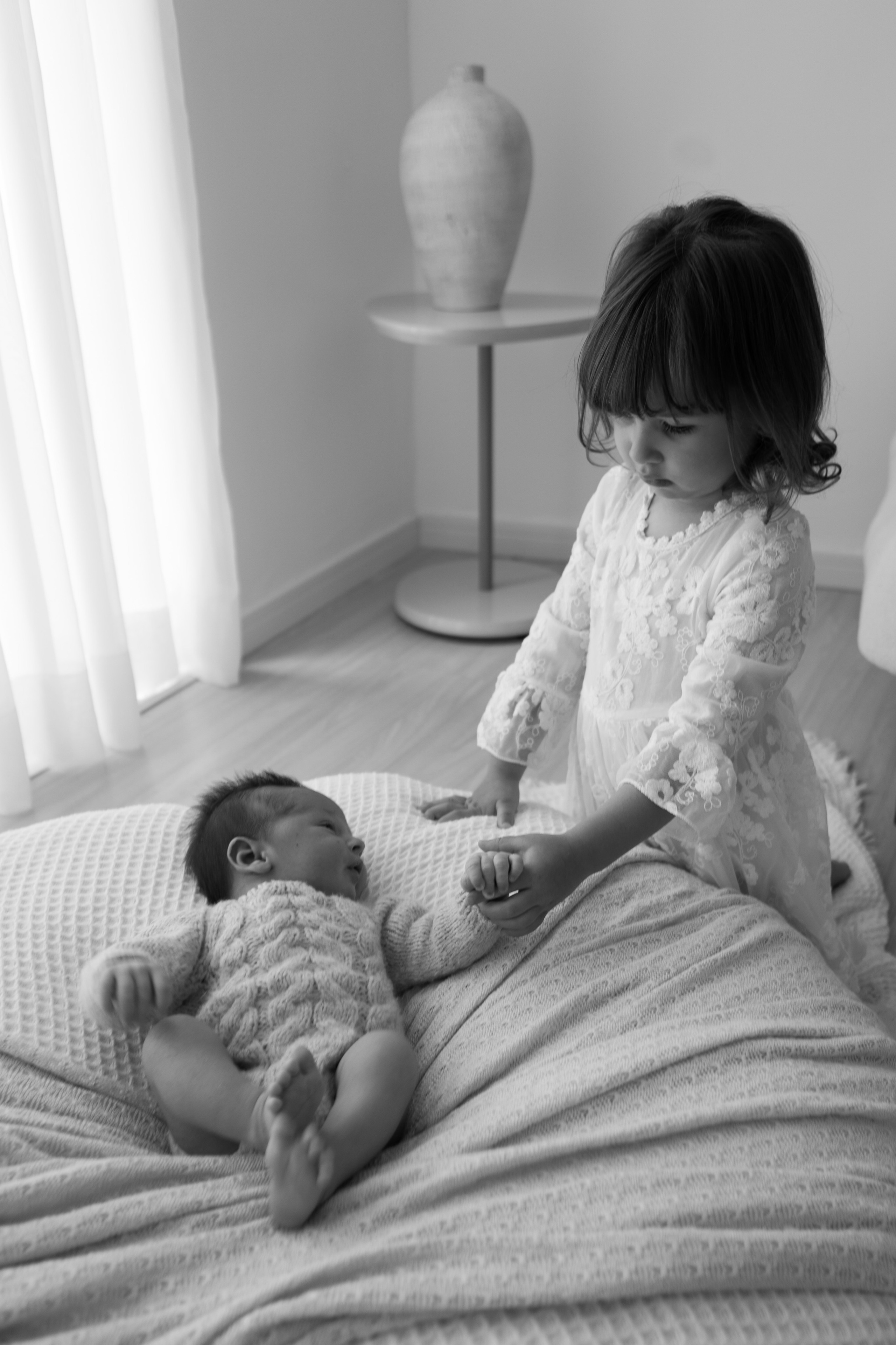 irmão mais velha observando bebê recém-nascido em ensaio em Sorocaba