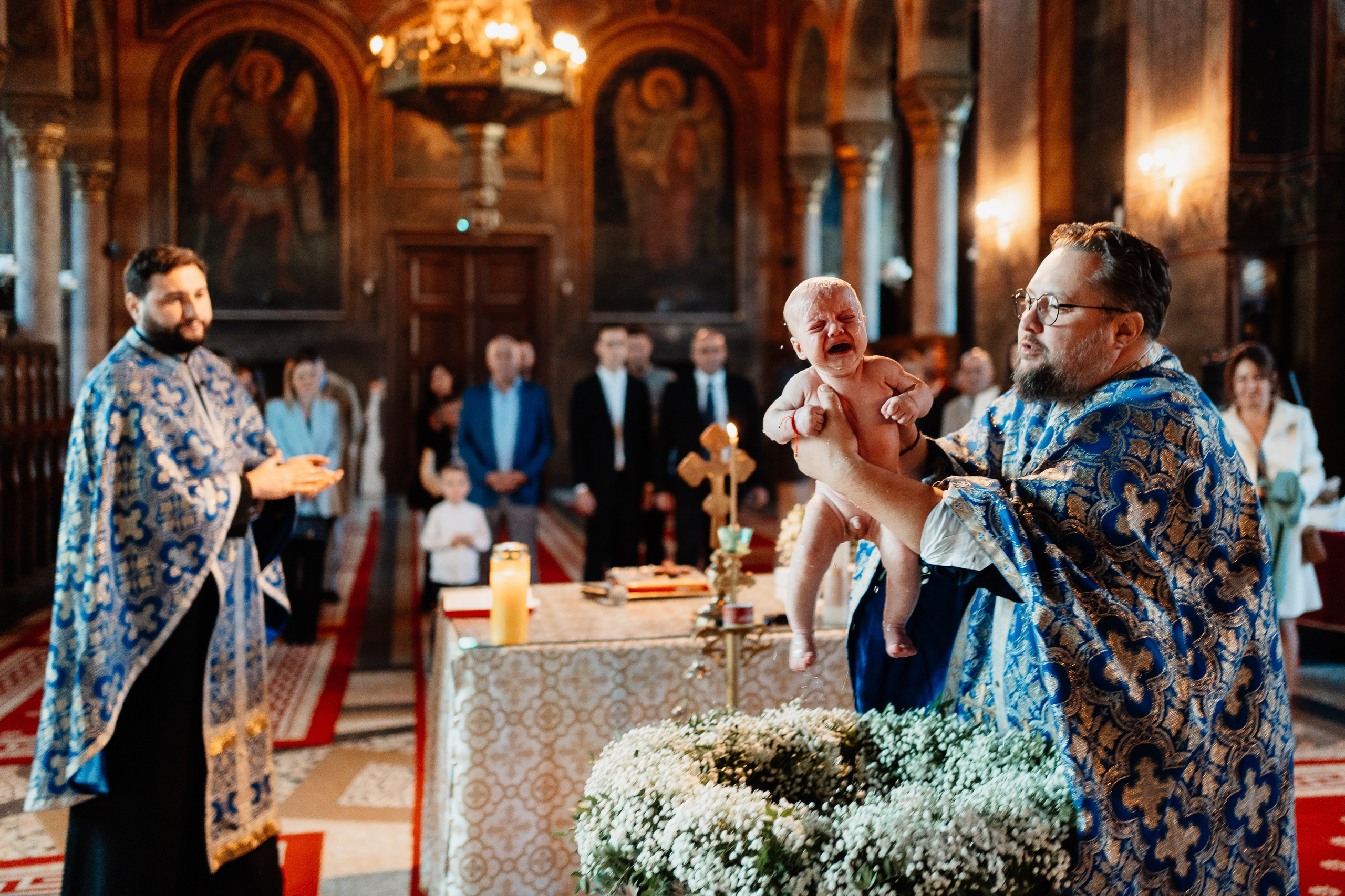 Instantaneu plin de tandrețe dintre părinți și bebeluș în ziua botezului, realizat în Craiova. Fotografie profesională de botez, capturând emoțiile autentice ale familiei într-un decor luminos și cald