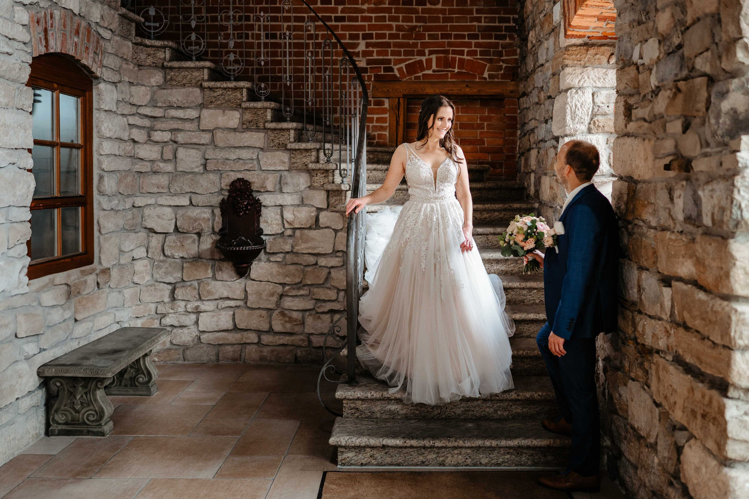 Eleganter First Look Brautpaar auf Steintreppe in historischer Location.