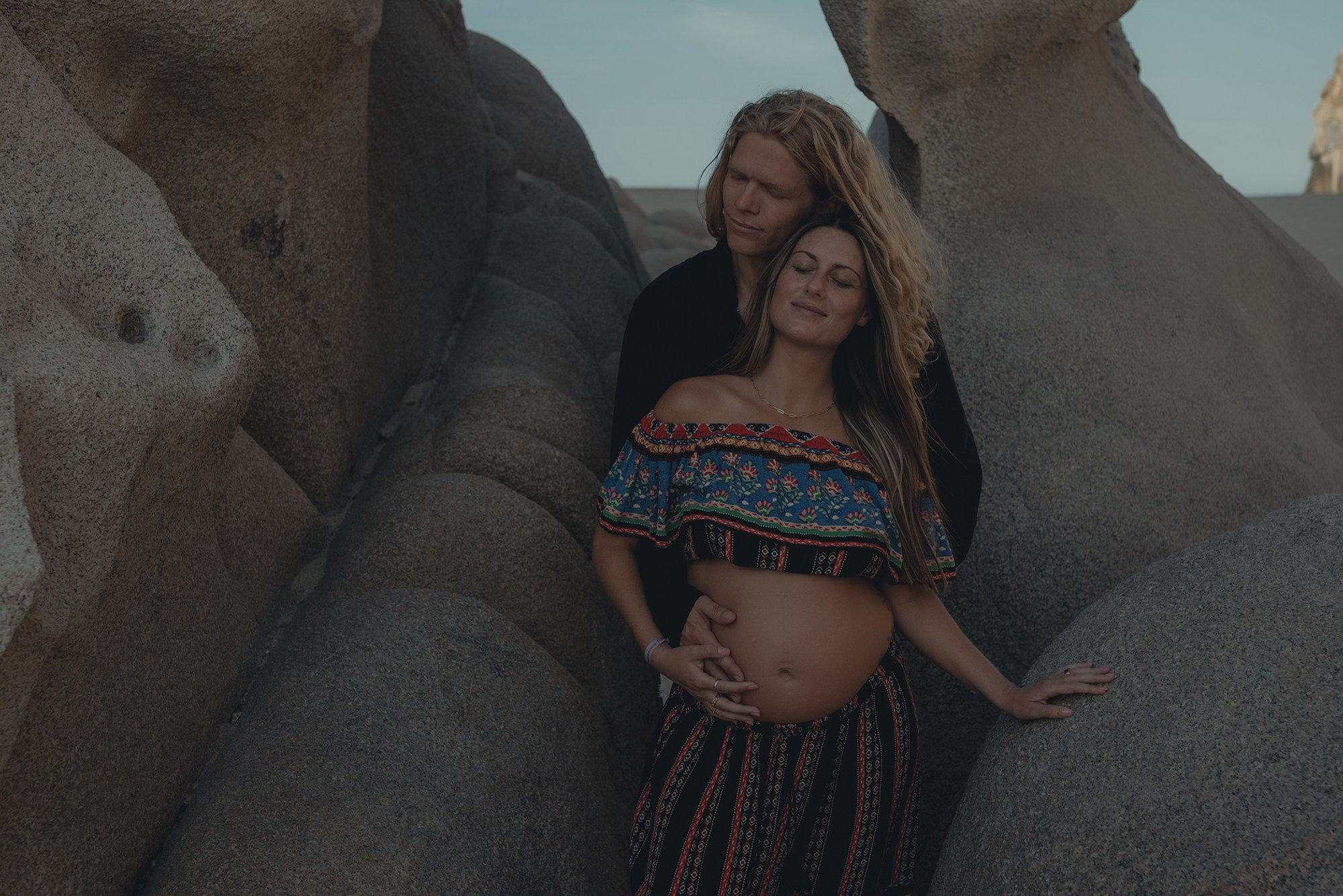 Cinematic maternity photoshoot in Playa del Amor, Los Cabos – pregnant mother and couple portraits with iconic rock formations, dramatic lighting and warm cinematic tones, destination maternity photographer in Baja California Sur