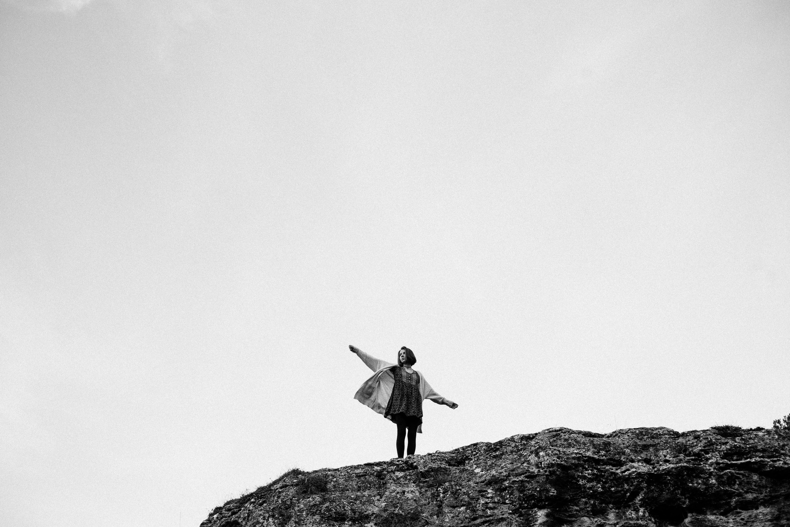 Person jumping on rocky landscape in black and white