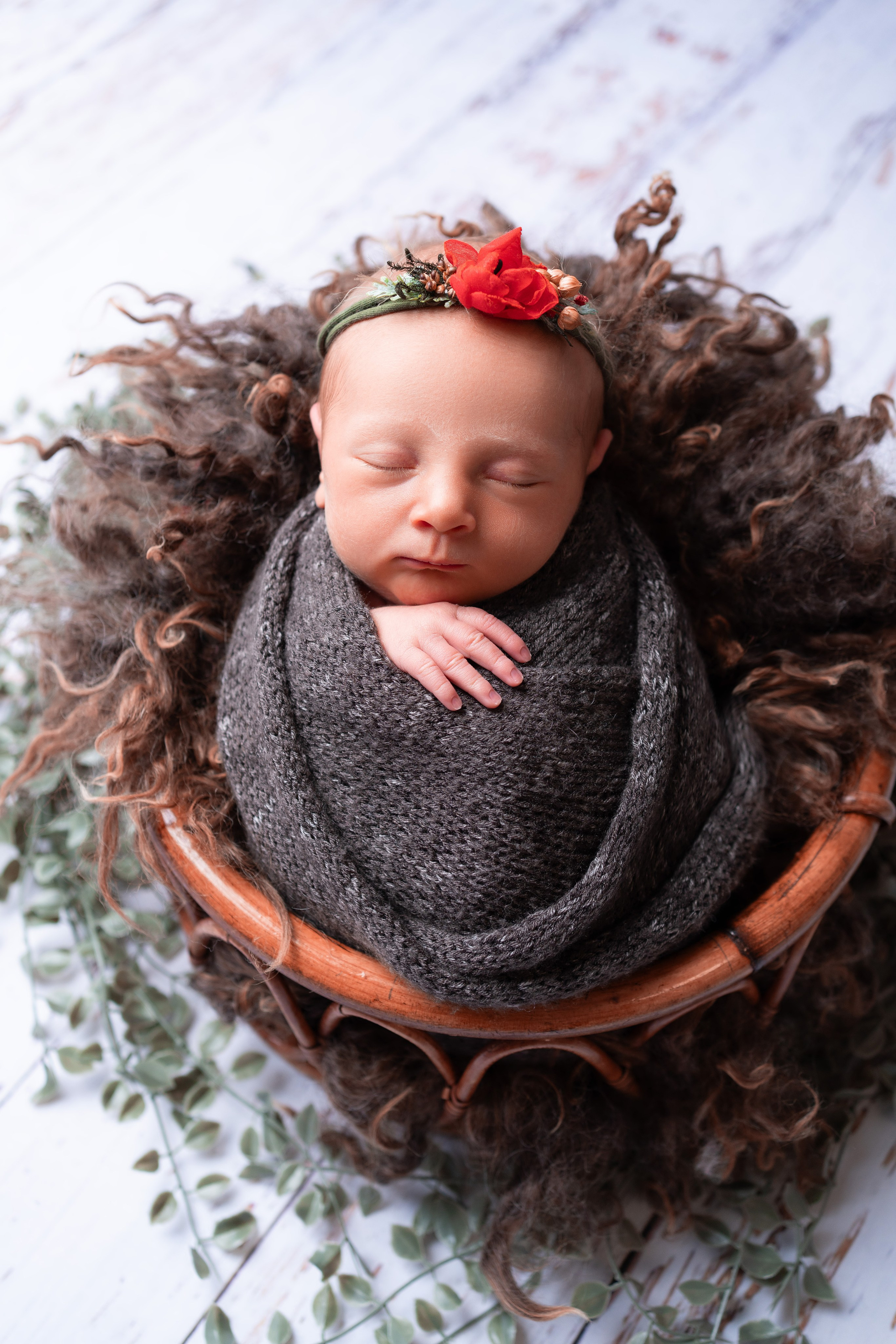 Neugeborener Schatz mit einem Kranz aus rotem Mohn auf dem Kopf