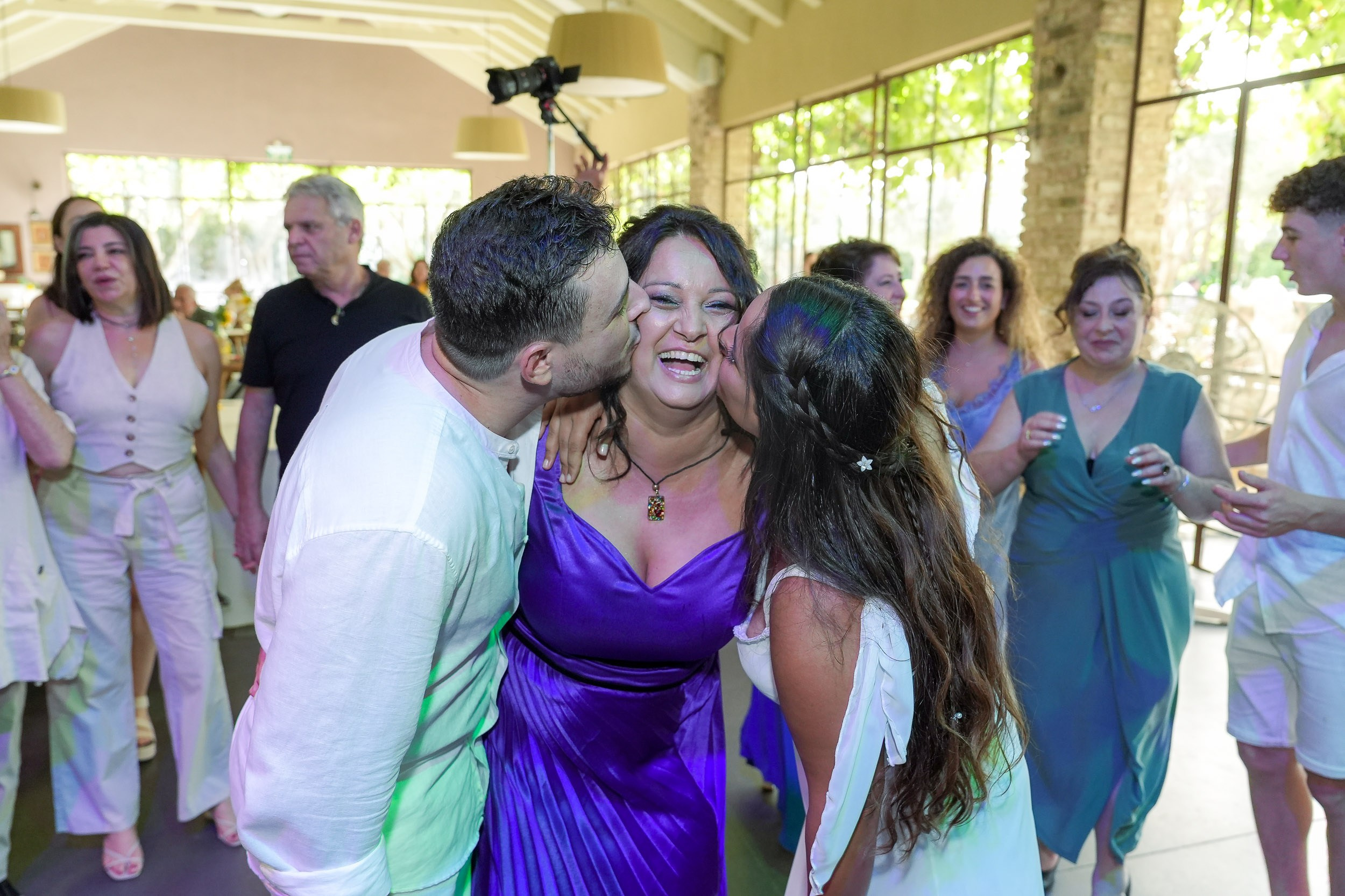 Talia and Ronen kiss their mother during the wedding reception