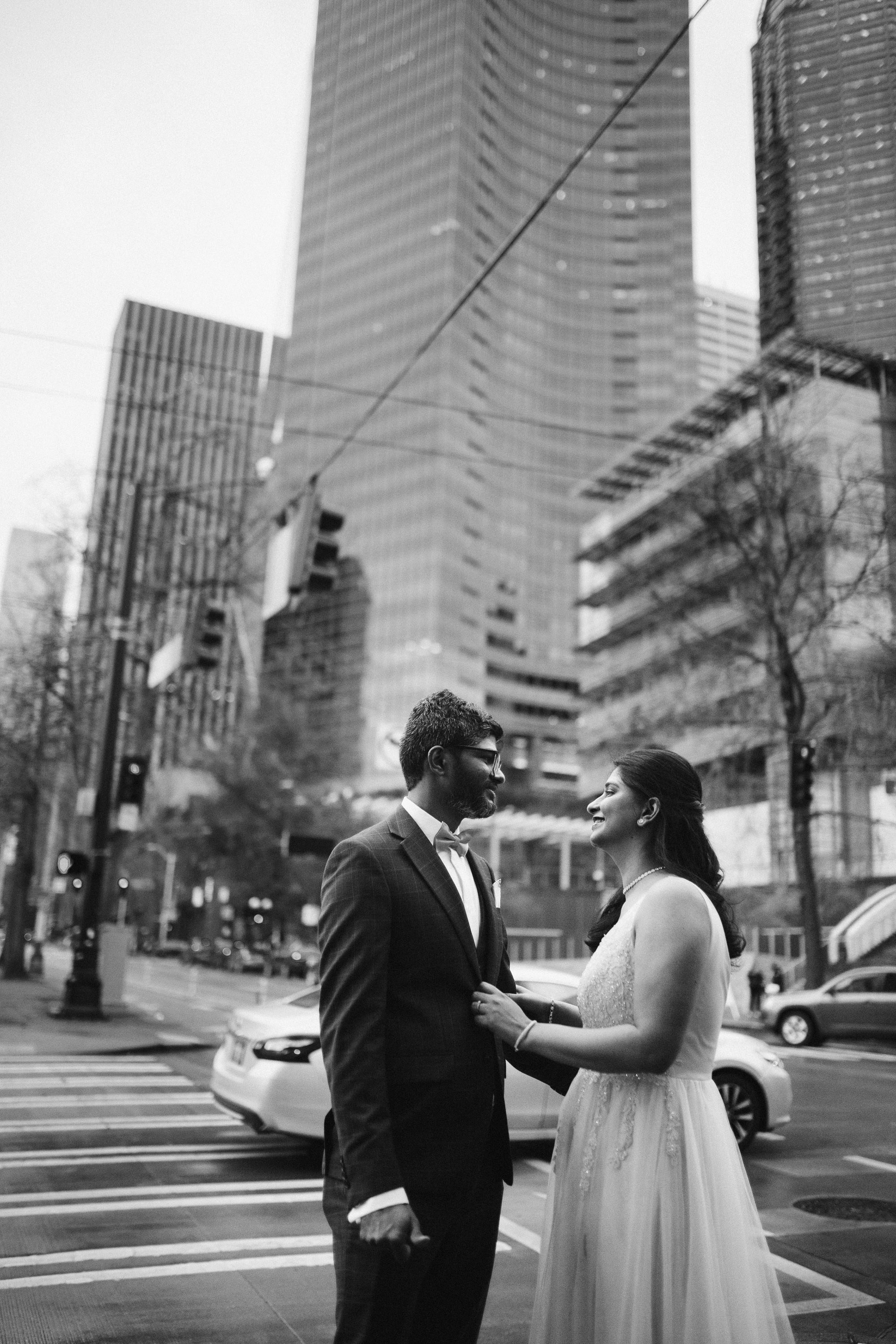Bride and groom walking in city, black and white urban portrait