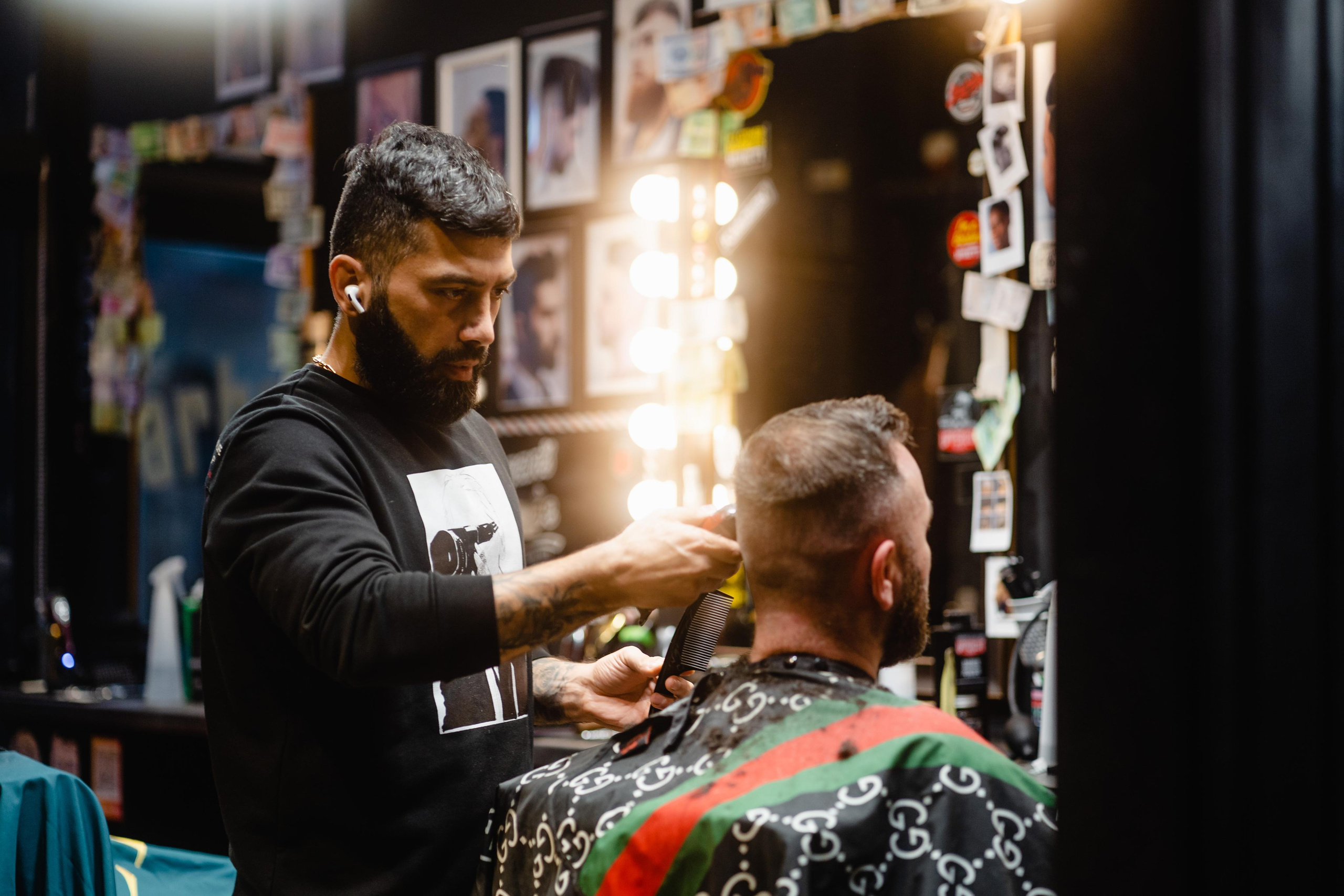 A barber styling a client’s hair in a lively barbershop filled with warm lights and vibrant decor