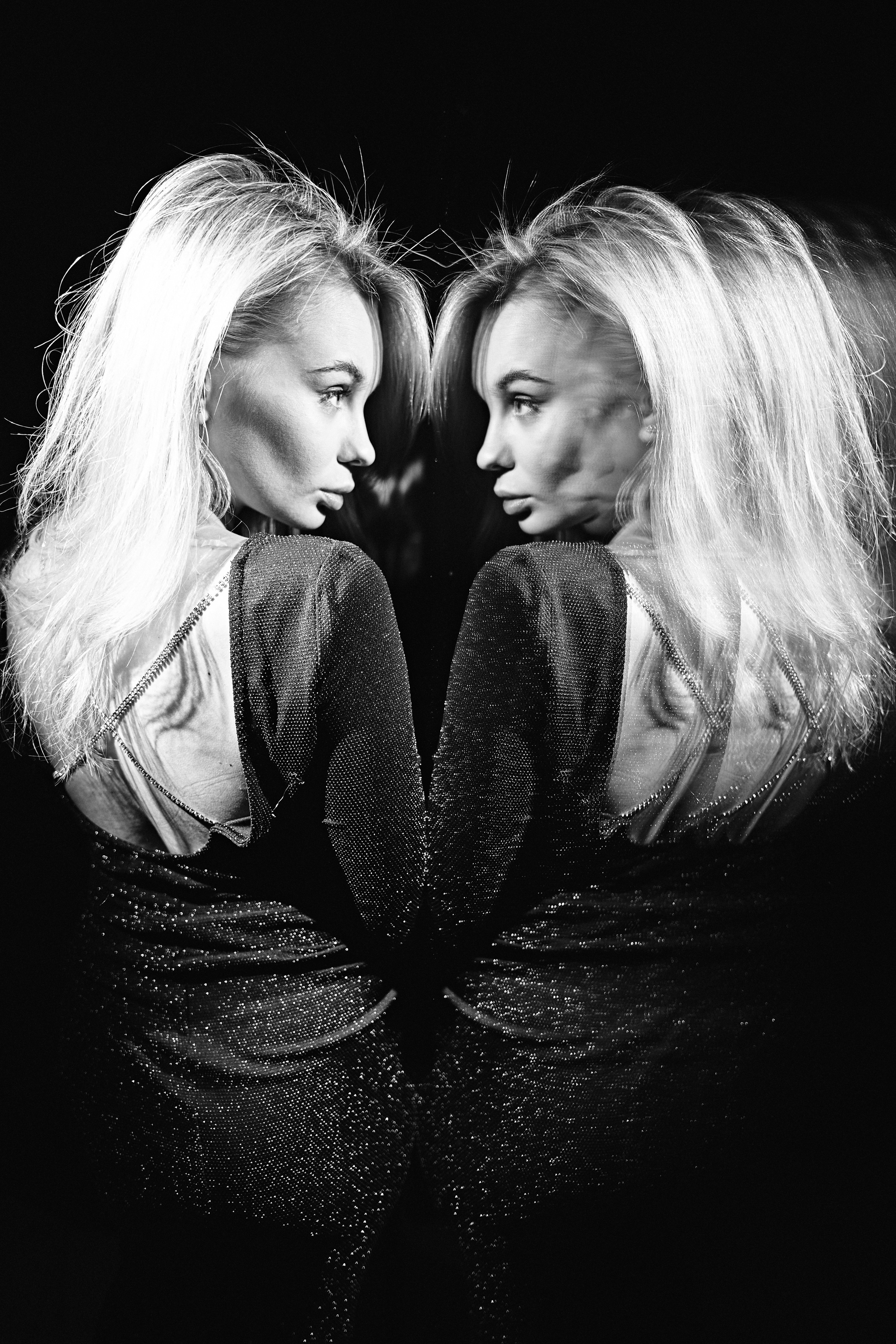 A monochrome portrait of twin women facing each other, their reflections mirroring elegance and mystery.