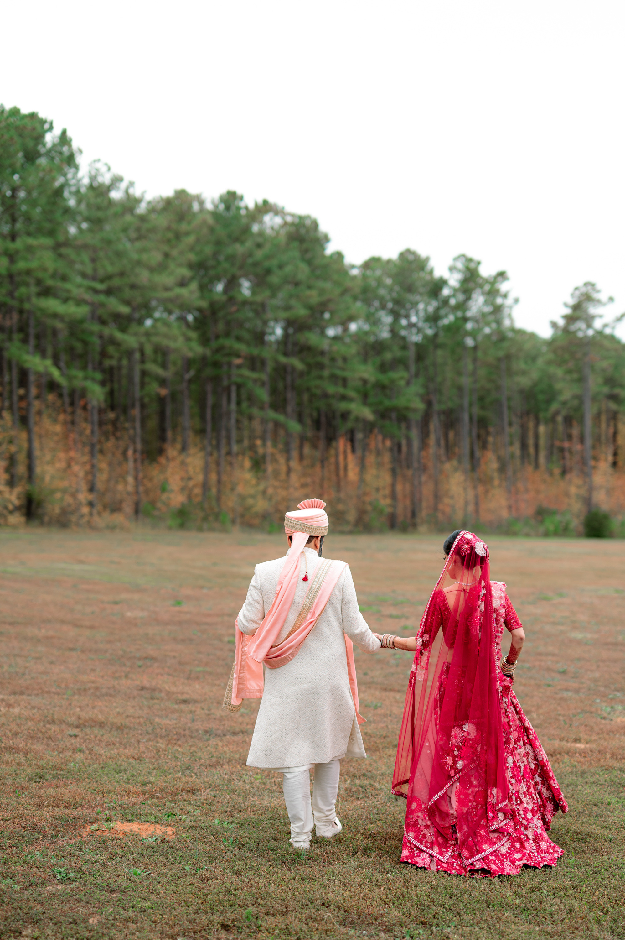 a couple in traditional indian attire walking through a field