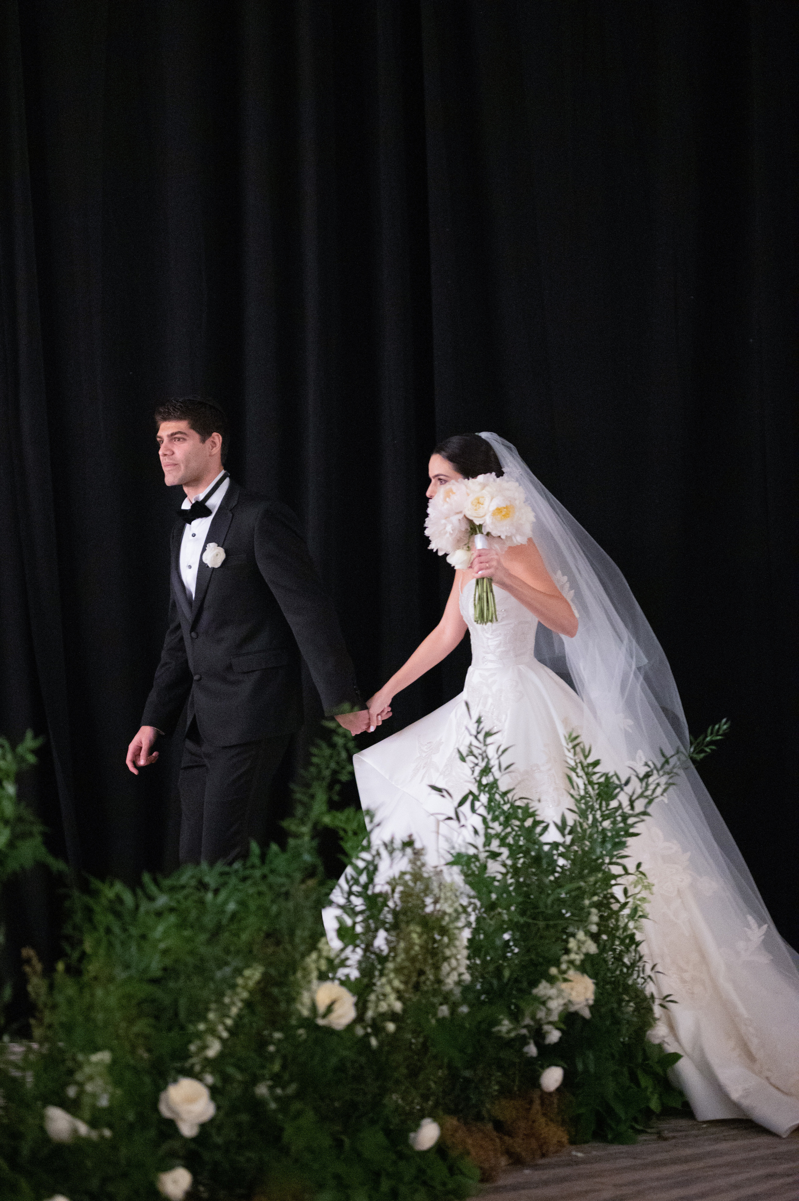 a bride and groom walking through a flower filled aisle
