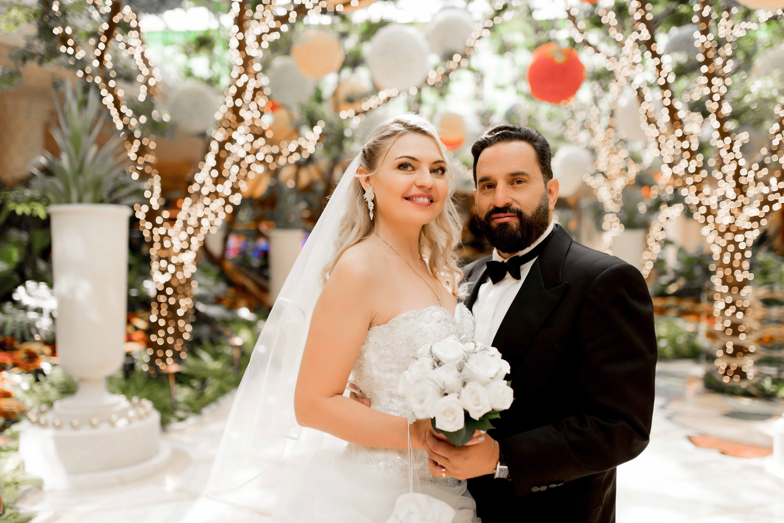 a bride and groom pose for a photo in front of a decorated tree