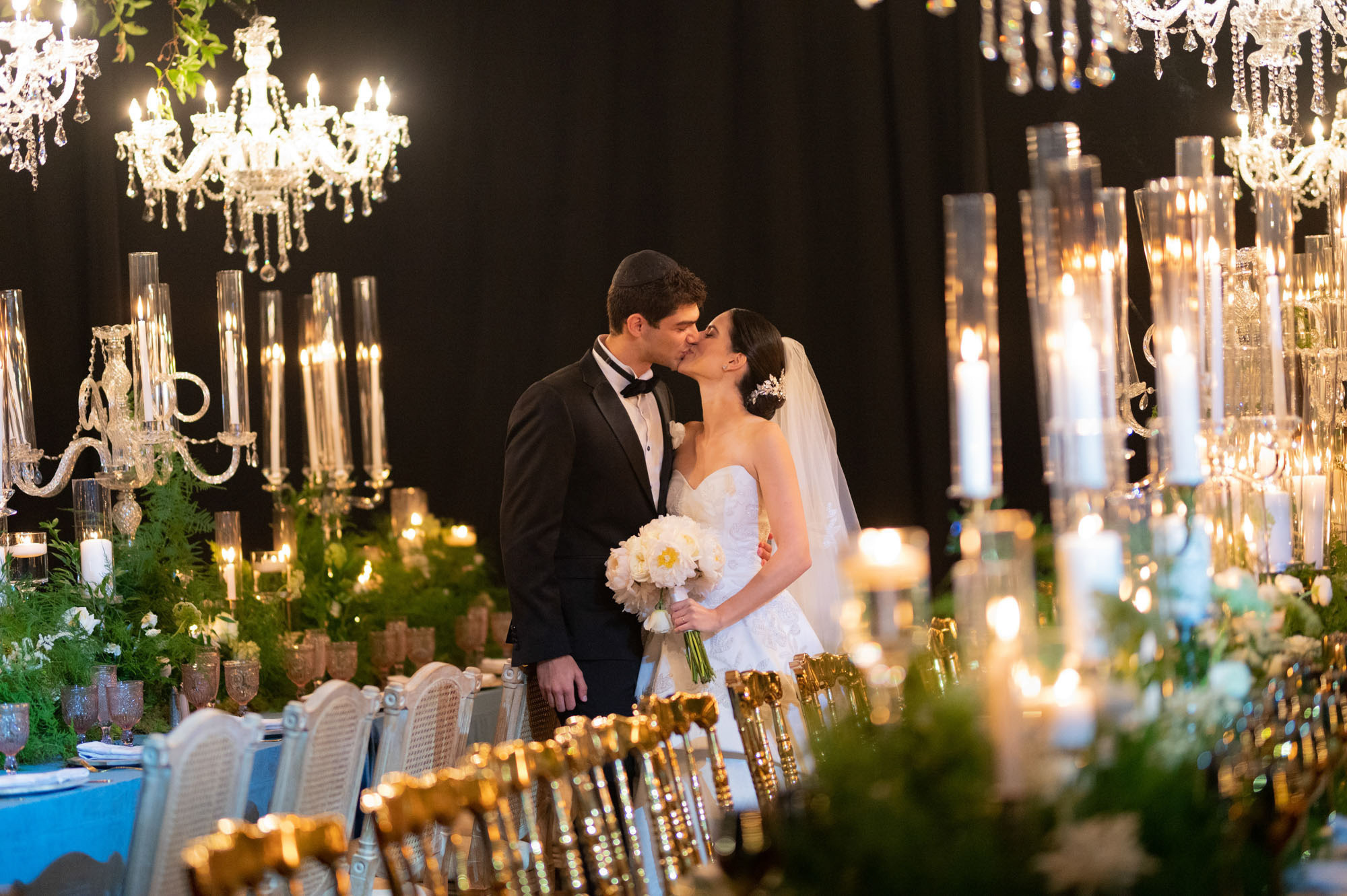 a bride and groom kissing in front of a table with candles