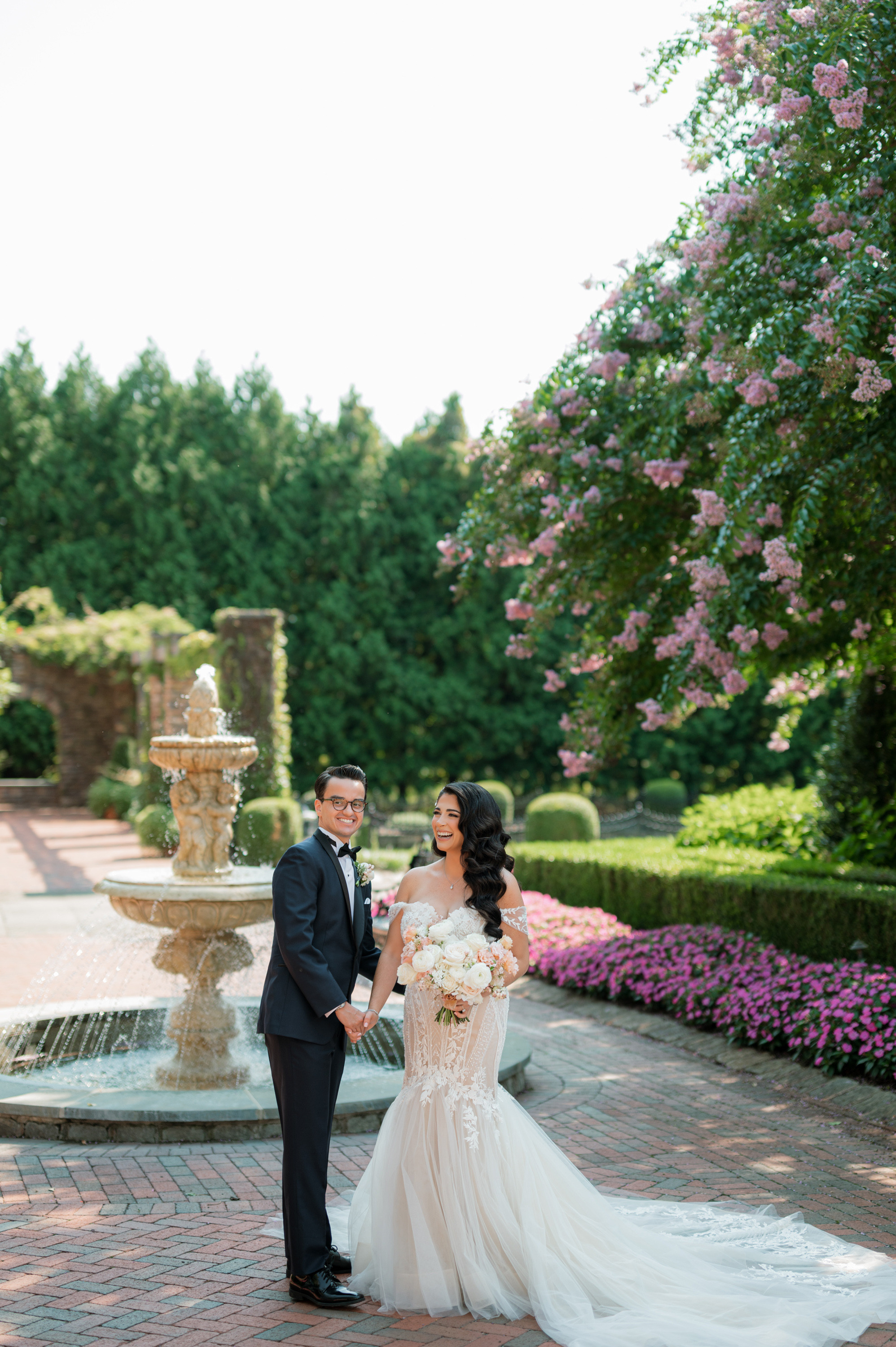a bride and groom pose for a photo in front of a fountain