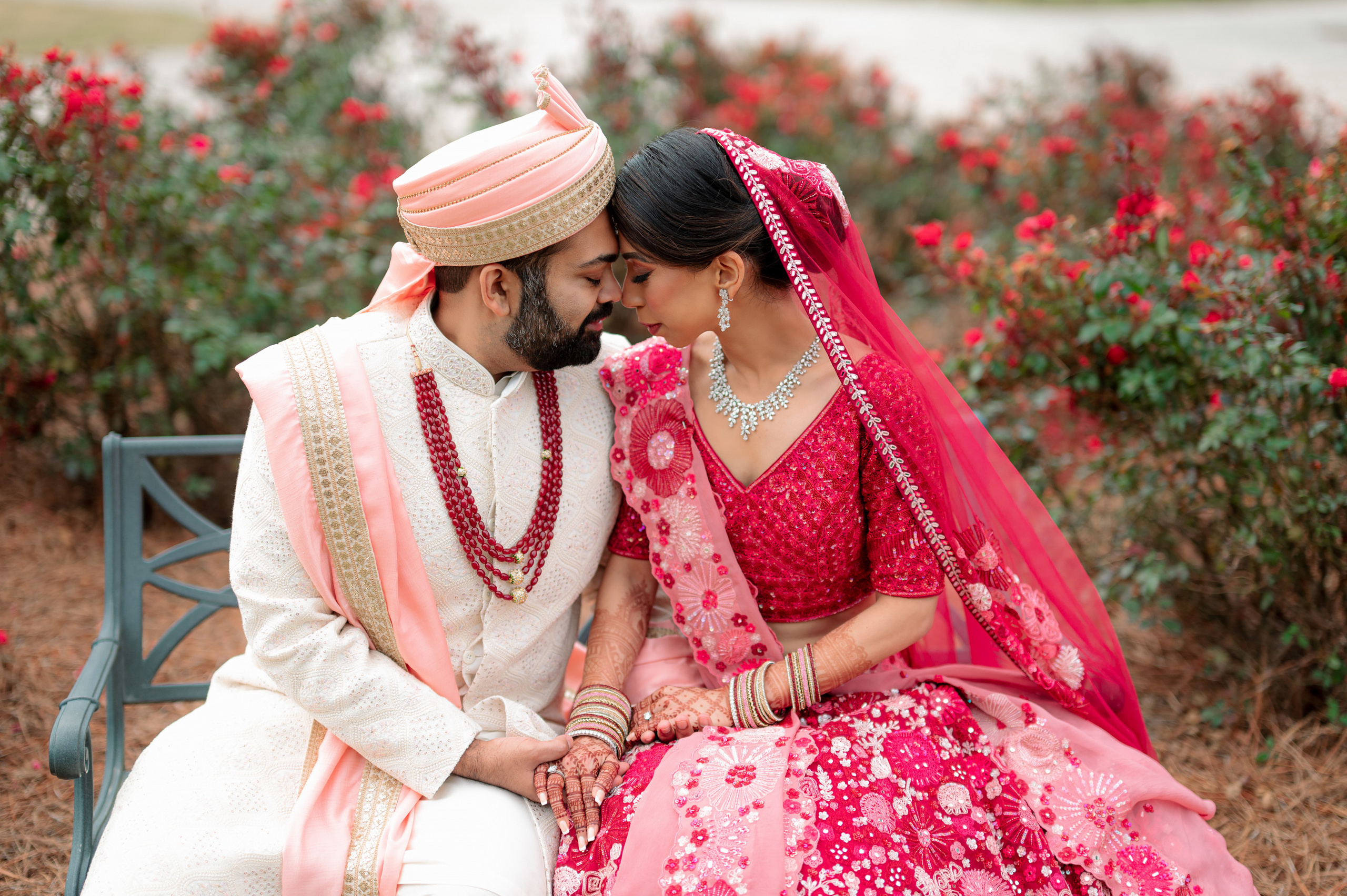 a couple sitting on a bench in front of flowers