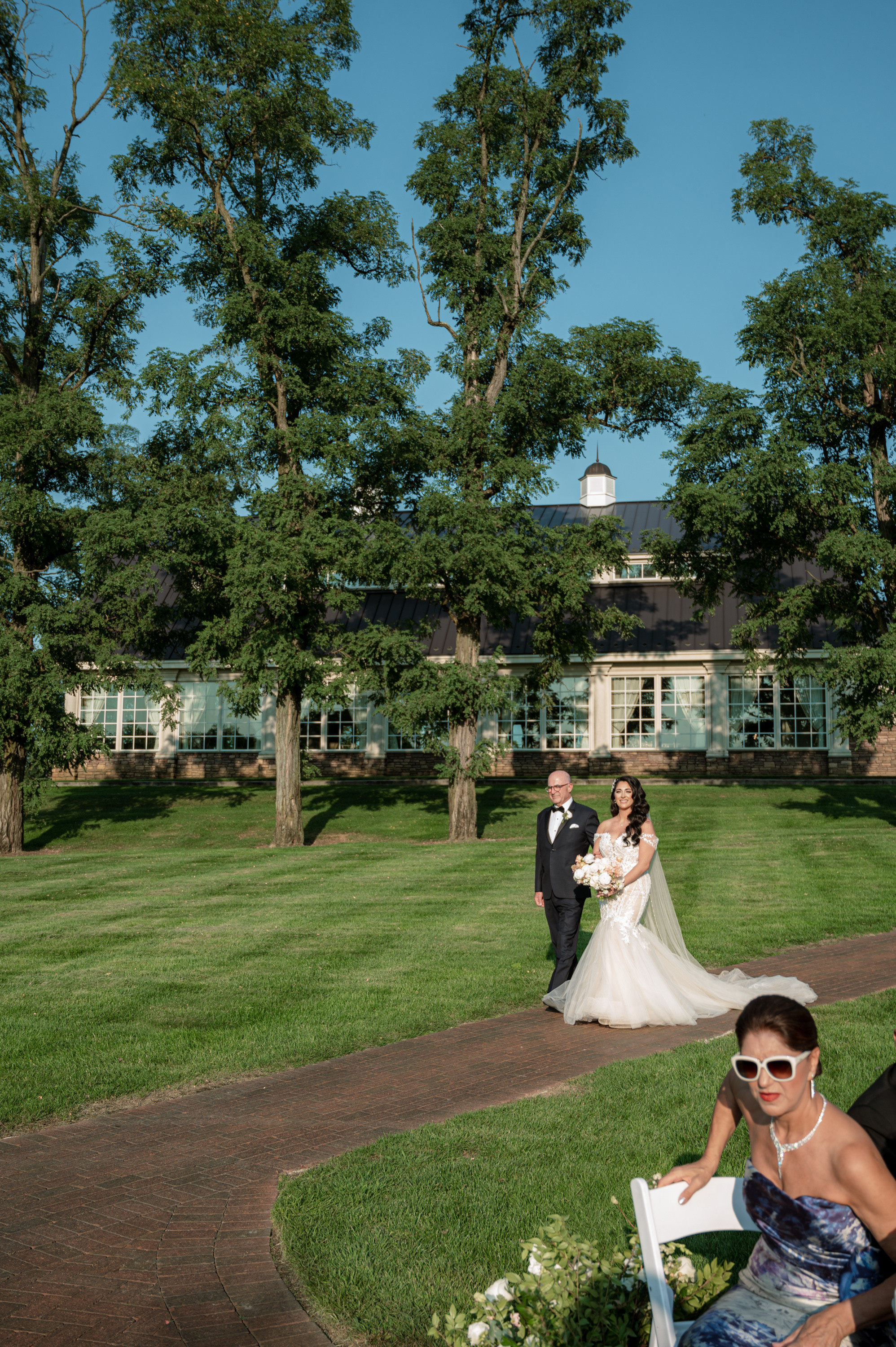a bride and groom sitting on a bench in a park